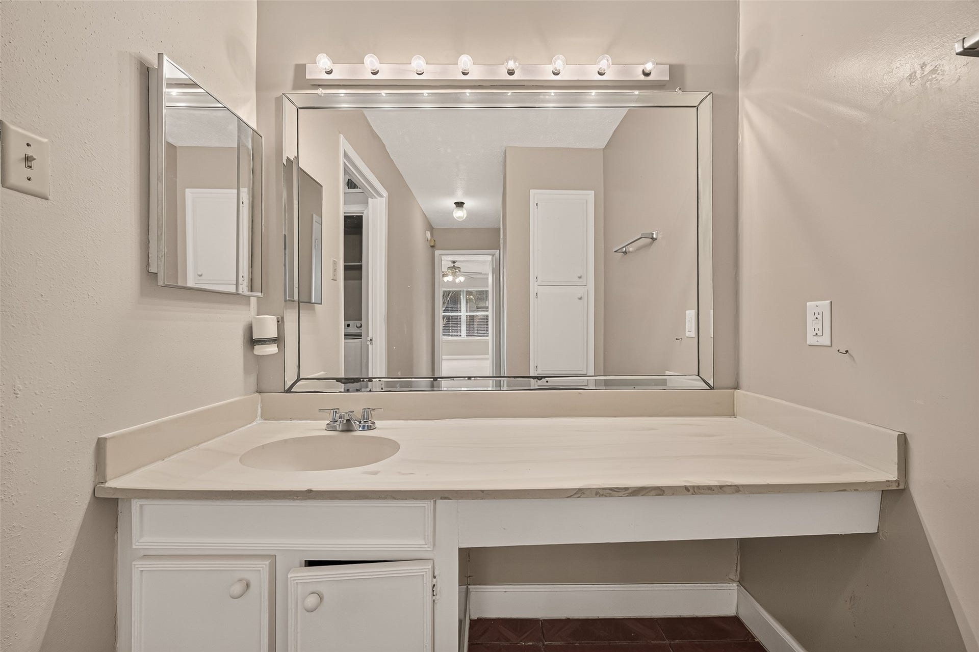 10555 Turtlewood Court, #1006, Houston, TX 77072 Spacious bathroom vanity with a large mirror and ample counter space, enhanced by soft lighting and neutral tones.