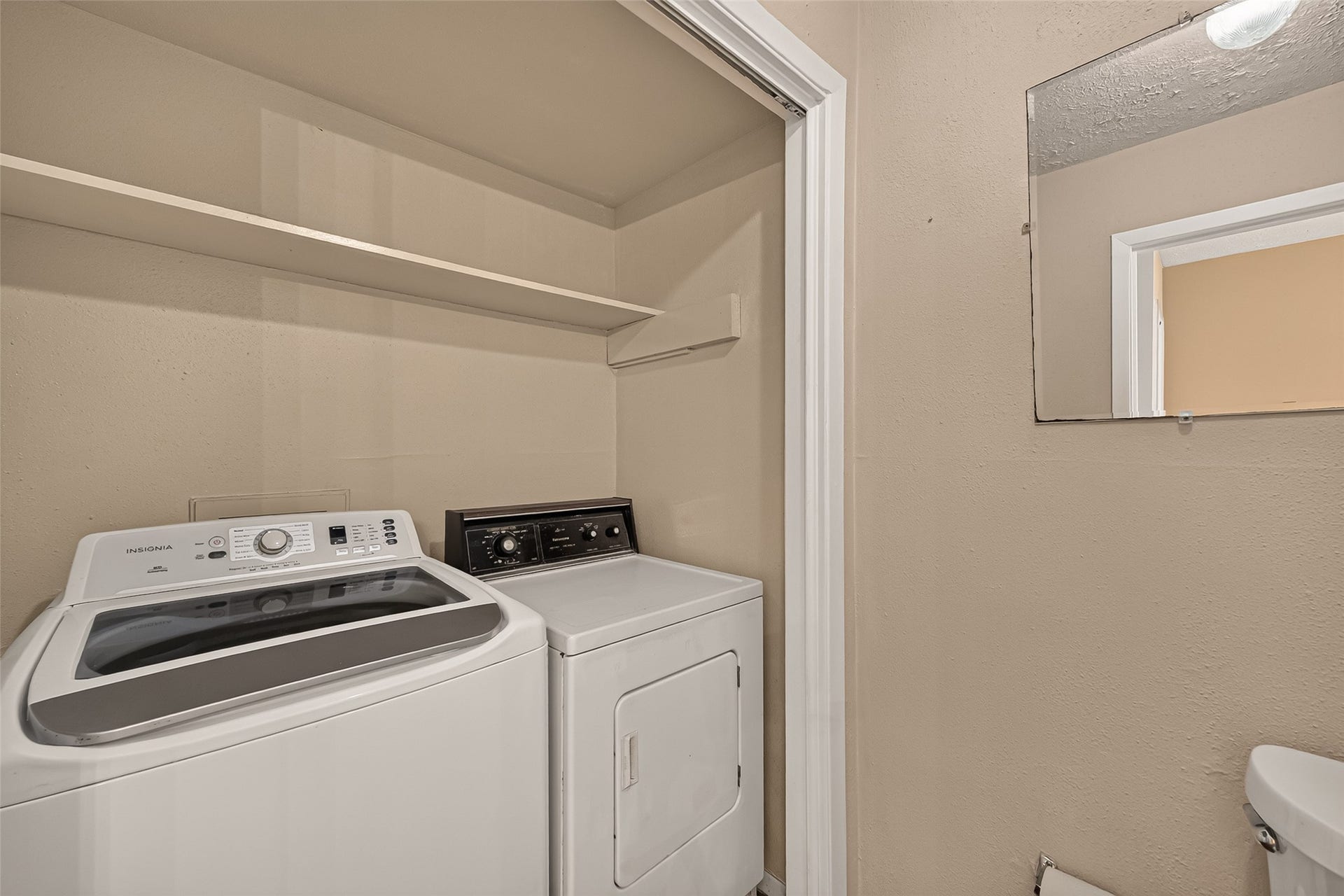 10555 Turtlewood Court, #1006, Houston, TX 77072 Convenient laundry area with washer and dryer, featuring overhead shelving for additional storage.