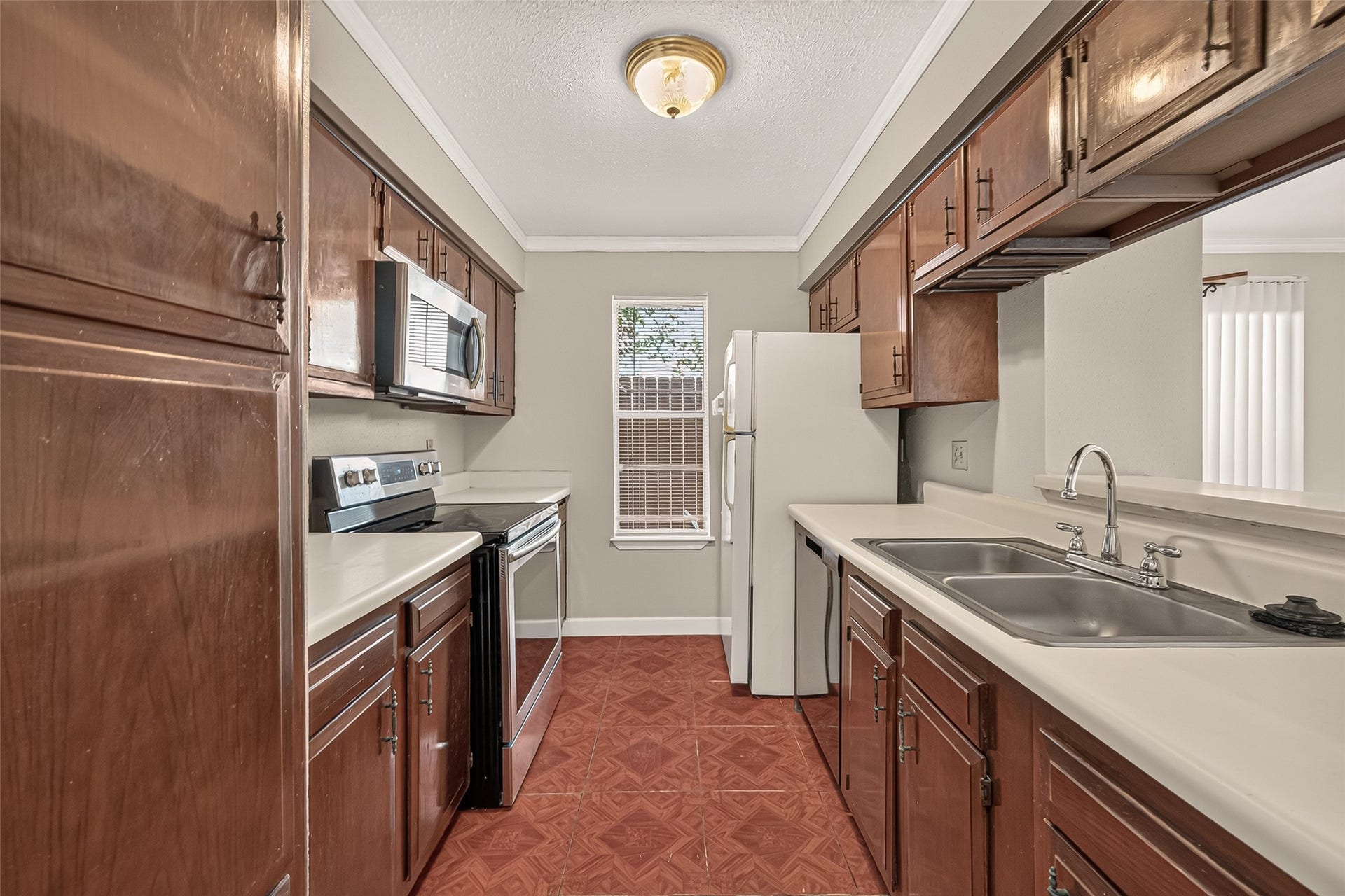 10555 Turtlewood Court, #1006, Houston, TX 77072 Charming kitchen features rich wood cabinetry and a cozy window allowing natural light to brighten the space.
