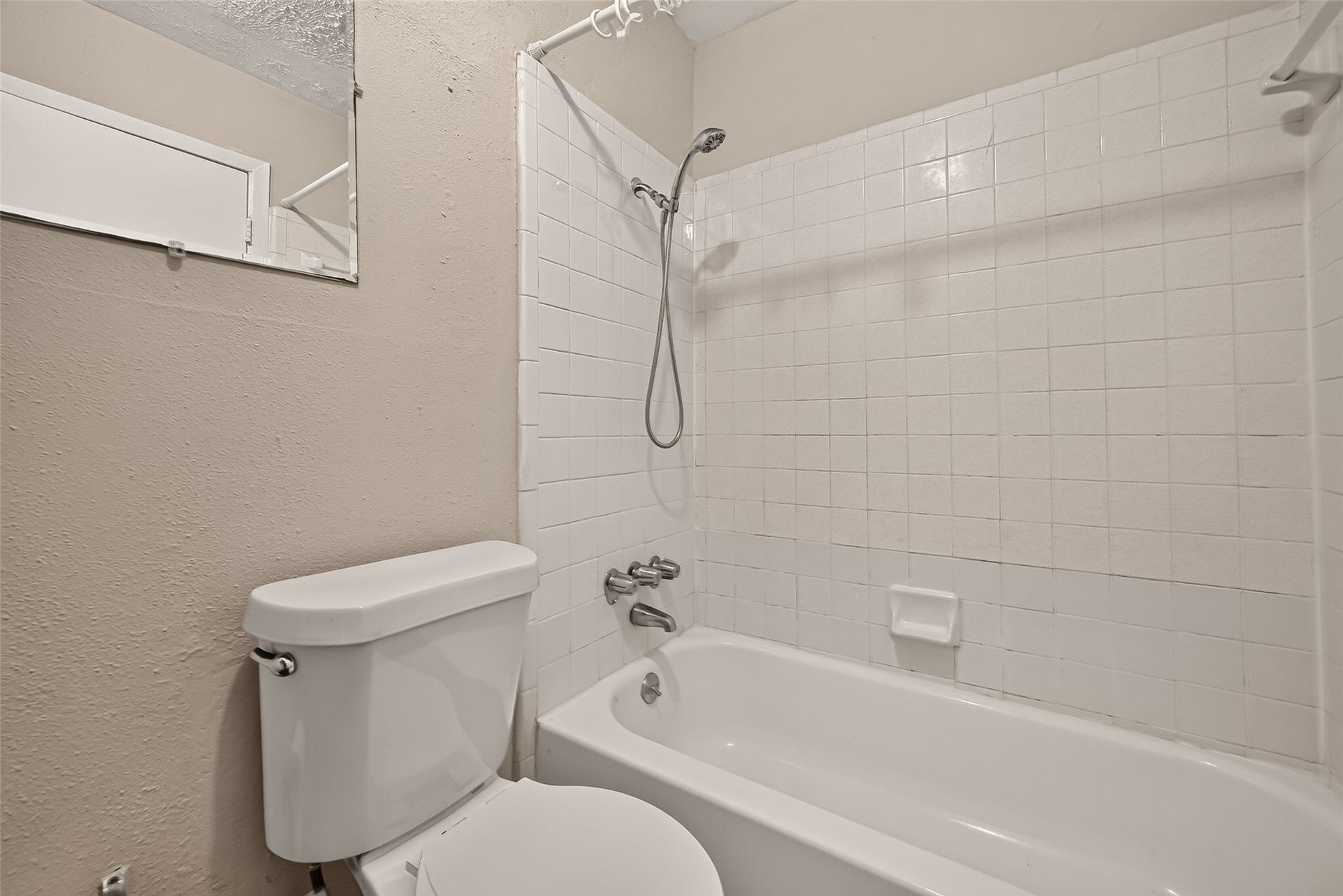 10555 Turtlewood Court, #1006, Houston, TX 77072 Cozy bathroom with a classic white tiled bathtub and shower combination, complemented by neutral walls for a clean and inviting feel.