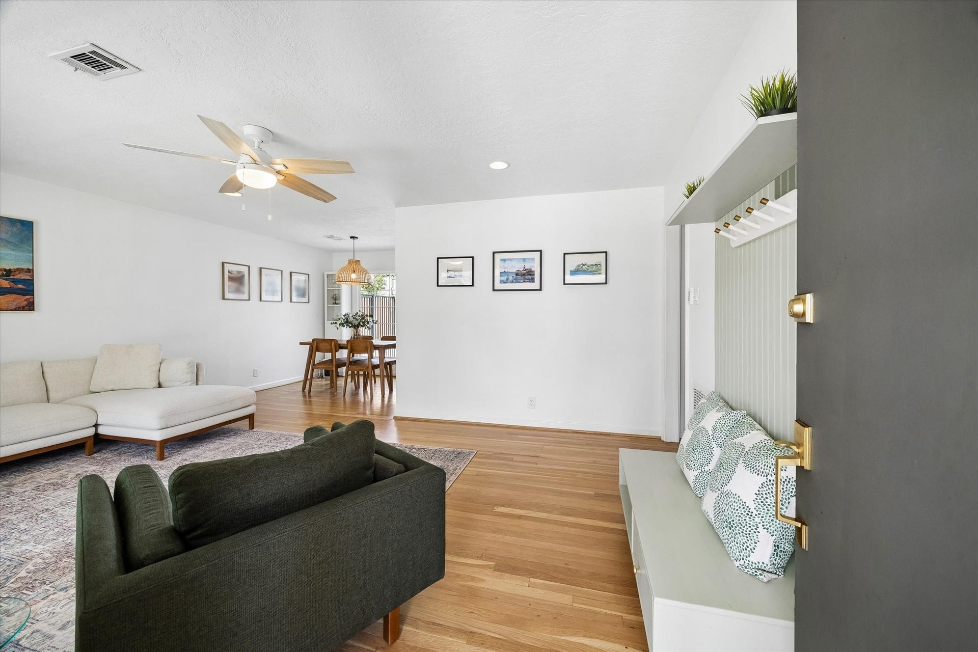 Welcoming entry opens to a bright, spacious living area with original hardwood floors, built in bench seating, and an easy flow into the dining space.