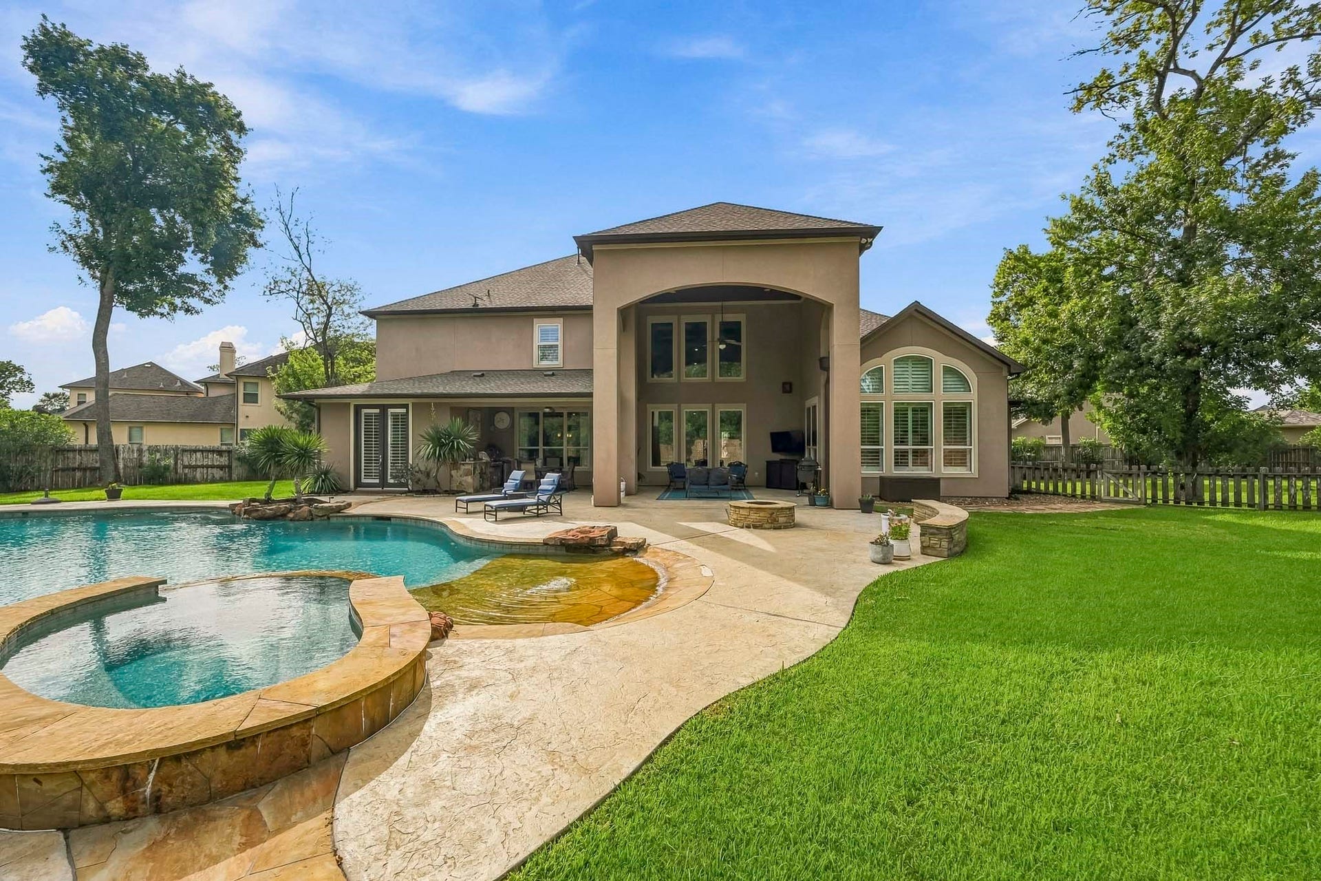 2 Turin Turn Drive, Missouri City, TX 77459 Stunning backyard oasis featuring a luxurious pool with spa, expansive patio space for outdoor lounging, and lush green lawn, all accentuated by a beautiful modern home exterior.