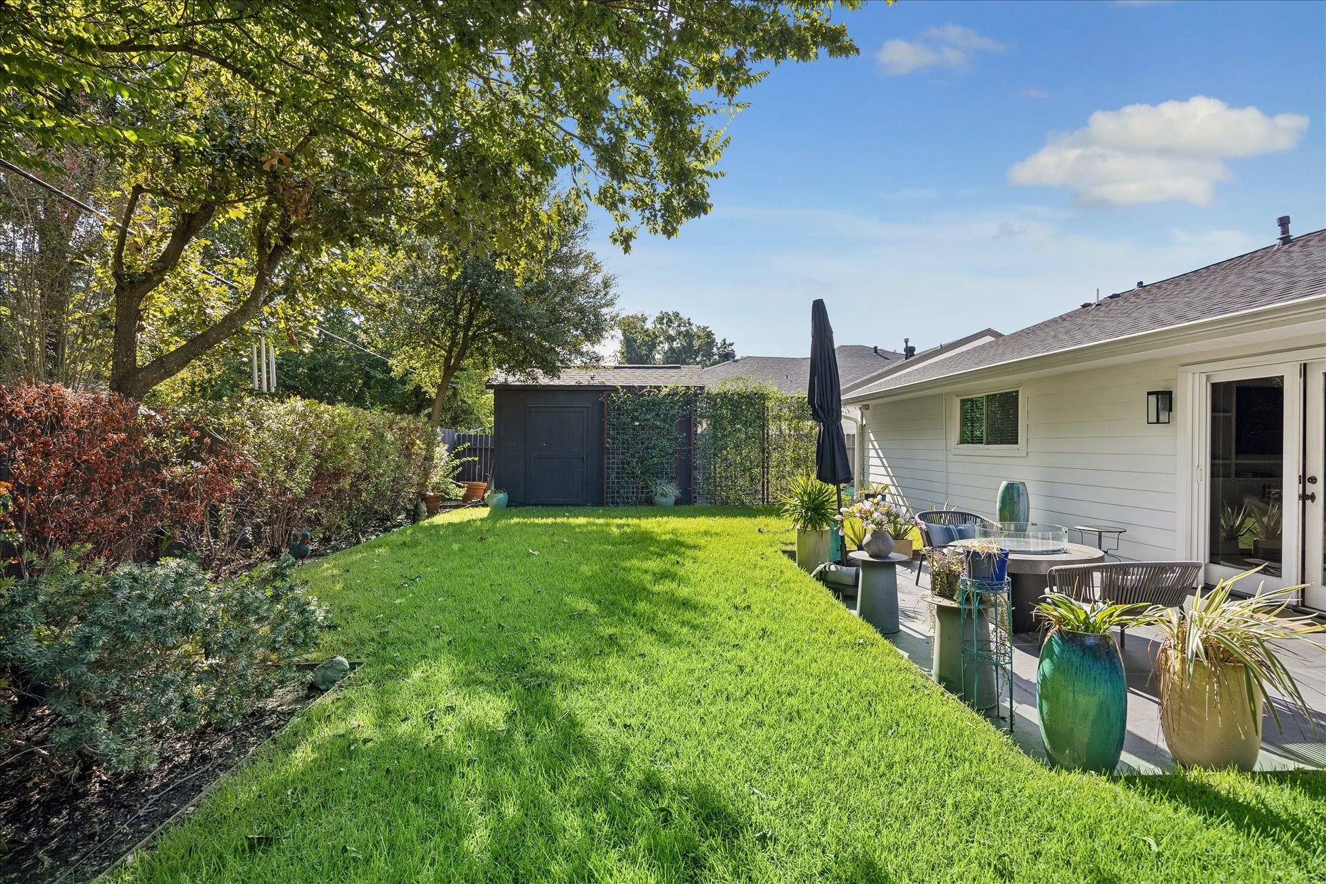 4130 Costa Rica Road, Houston, TX 77092 Mature trees frame the expansive lawn, with a welcoming patio and garden shed completing this peaceful outdoor retreat.