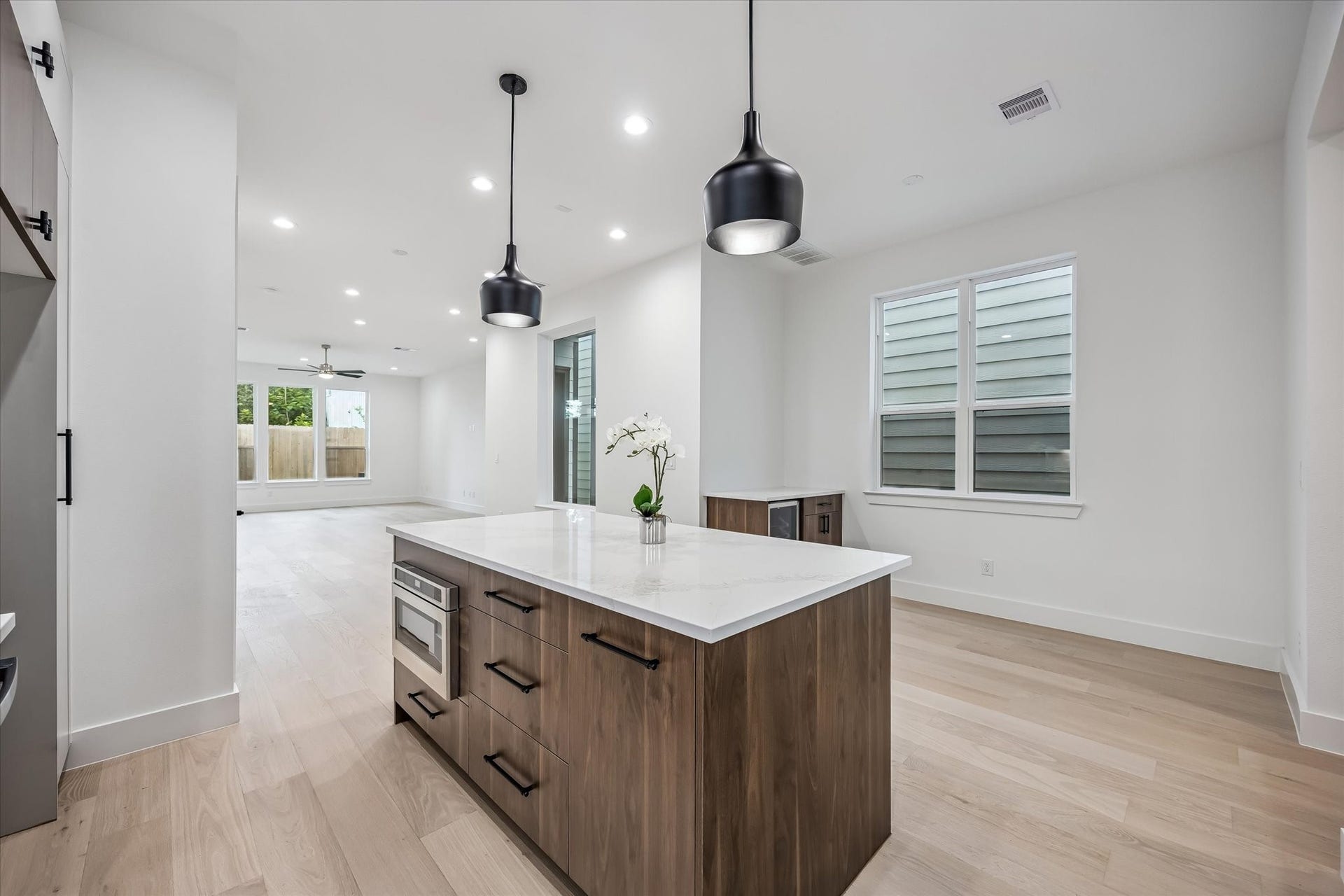 5339 Larkin Street, Houston, TX 77007 Sleek modern kitchen featuring a spacious island with elegant pendant lighting, opening to a bright, airy living area with large windows.