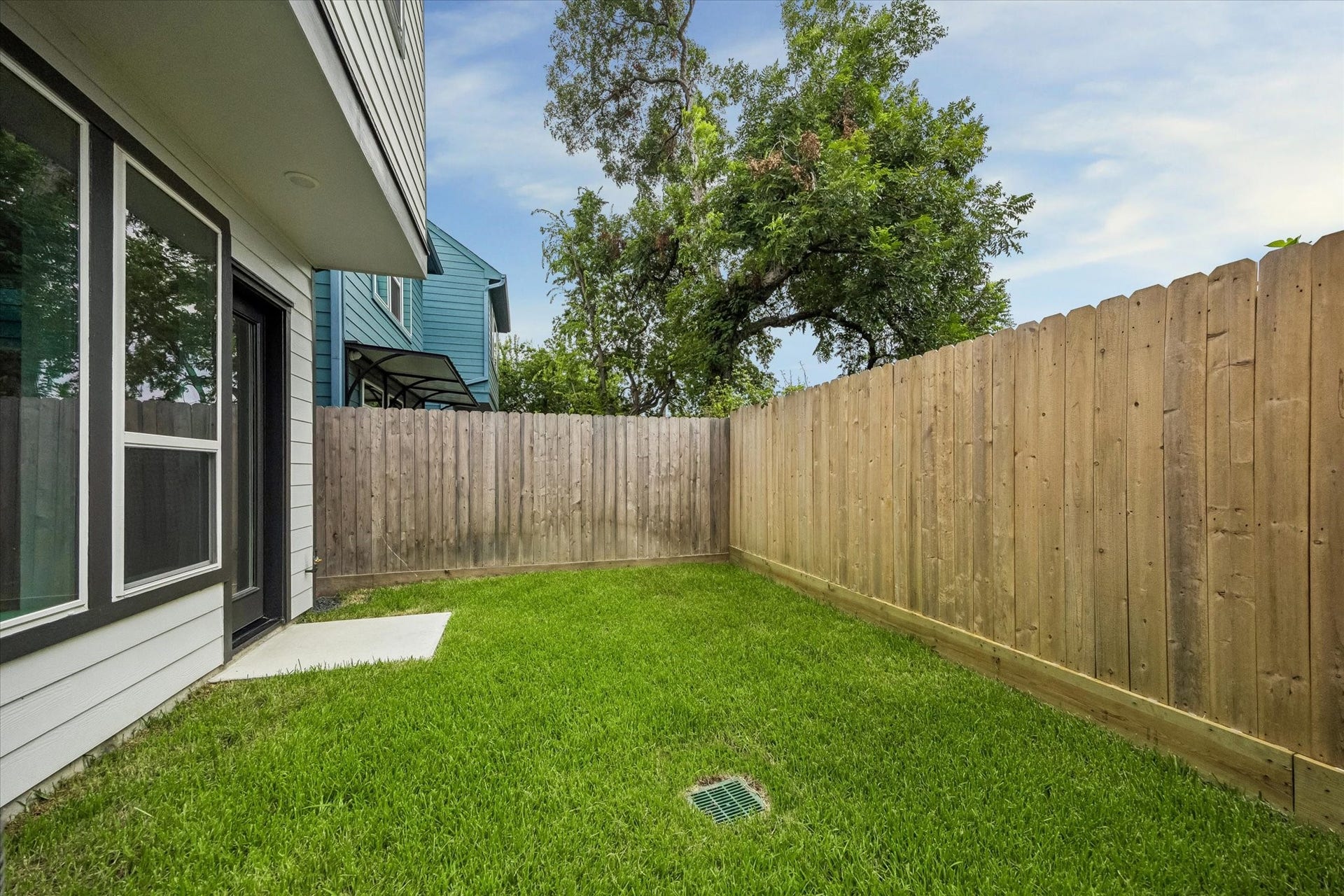 5339 Larkin Street, Houston, TX 77007 Charming fenced backyard with lush green lawn, perfect for privacy and relaxation.
