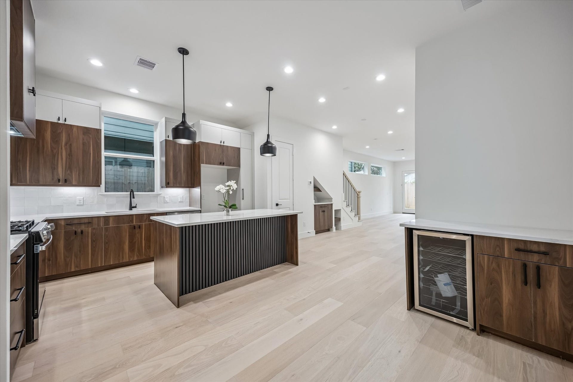 5339 Larkin Street, Houston, TX 77007 Sleek and modern kitchen featuring an island with pendant lighting, elegant wood cabinetry, and a built-in wine cooler.
