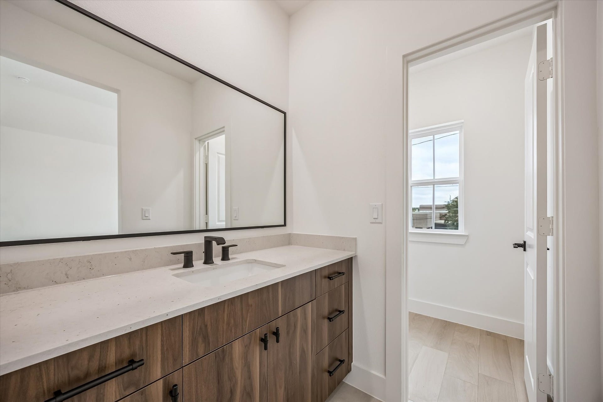 5339 Larkin Street, Houston, TX 77007 Sleek bathroom featuring a spacious vanity with modern fixtures, elegant wood cabinetry, and a large mirror, offering a bright and airy feel.