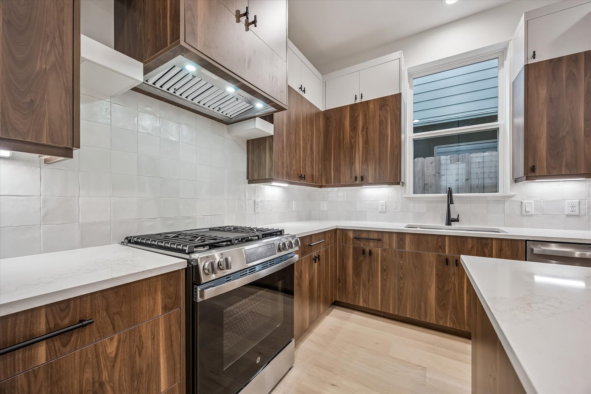 5339 Larkin Street, Houston, TX 77007 Modern kitchen with sleek wood cabinetry, stainless steel appliances, and elegant white countertops, creating a stylish and functional space.
