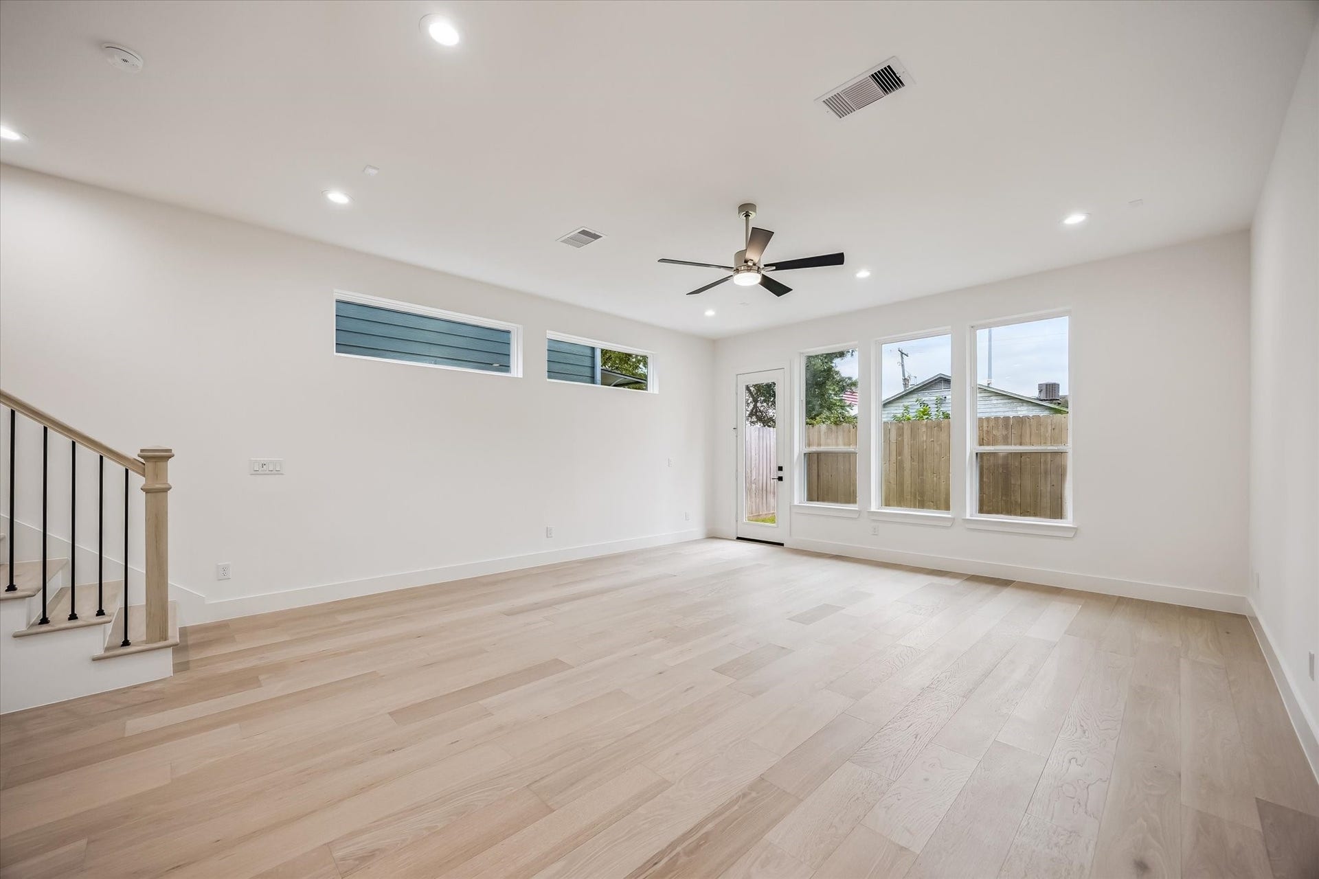 5339 Larkin Street, Houston, TX 77007 Spacious, light-filled living area with sleek hardwood floors, modern ceiling fan, and large windows offering backyard views.