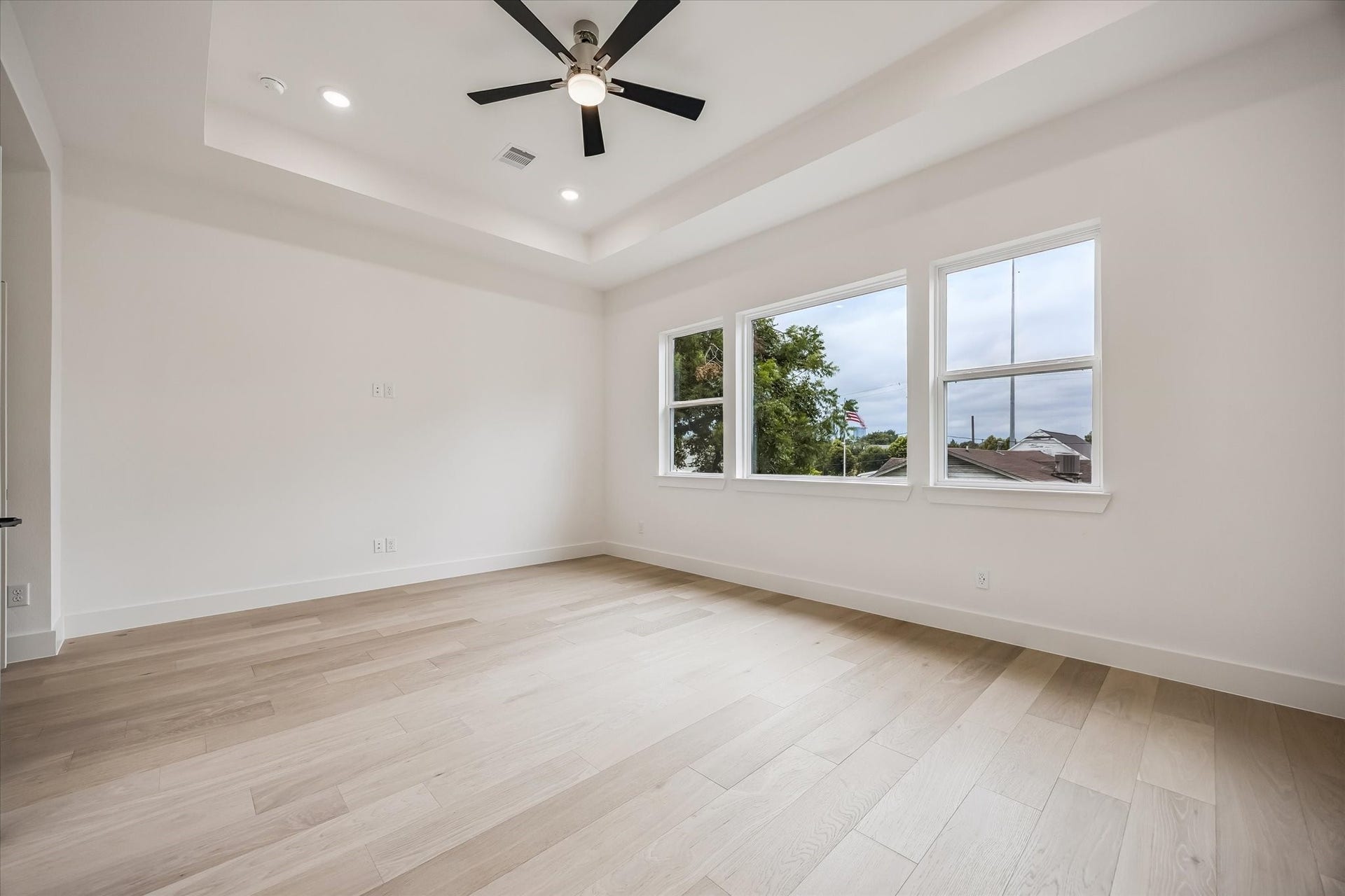 5339 Larkin Street, Houston, TX 77007 Bright and spacious room featuring elegant hardwood floors, large windows for natural light, and a modern ceiling fan set within a chic tray ceiling.