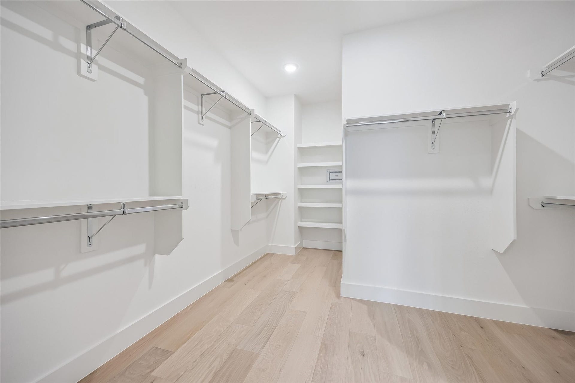 5339 Larkin Street, Houston, TX 77007 Spacious walk-in closet featuring ample hanging space, sleek shelving, and modern light wood flooring for a clean, organized look.