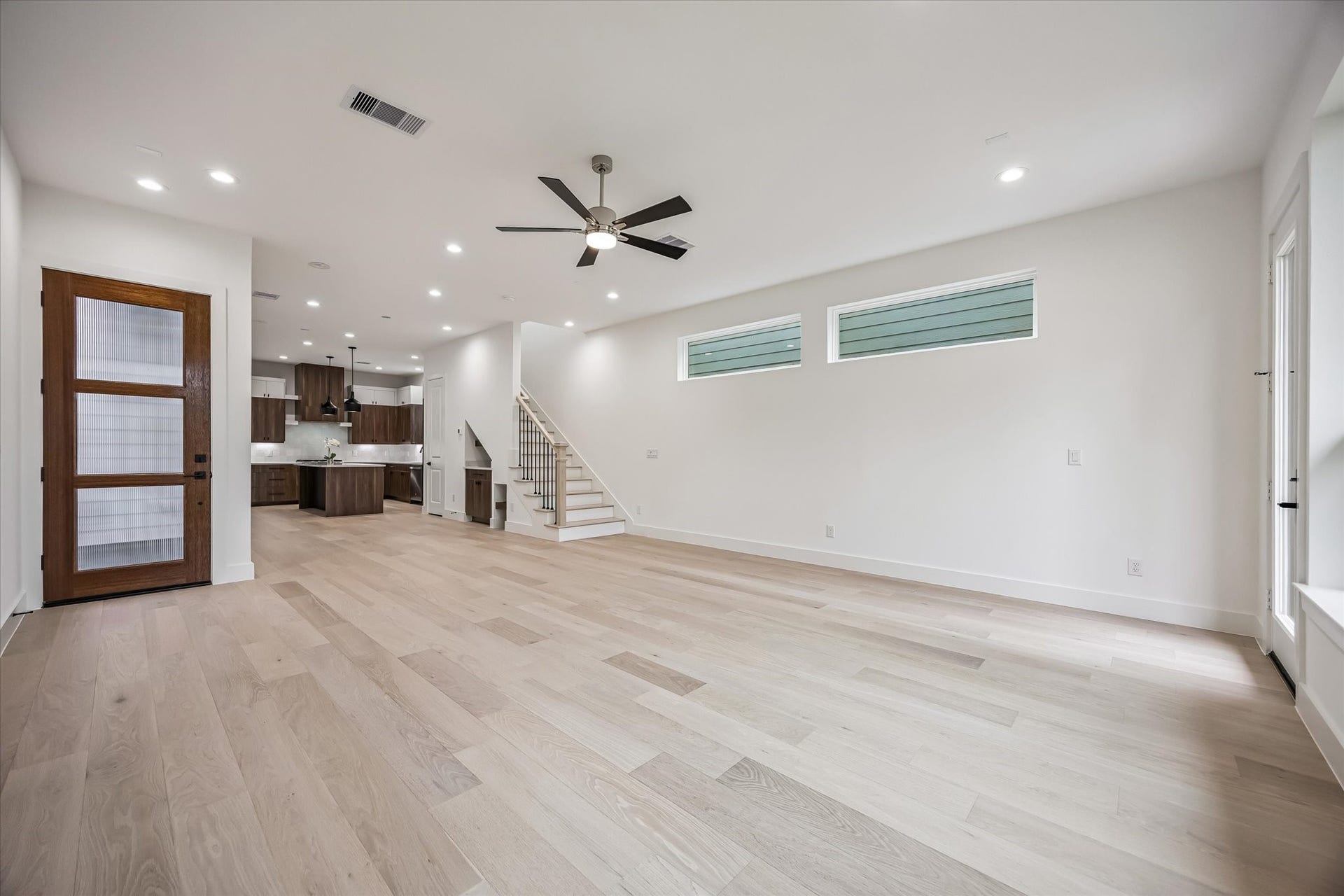 5339 Larkin Street, Houston, TX 77007 Spacious open-concept living area with light wood flooring and modern finishes, featuring a stylish kitchen with dark cabinetry, sleek countertops, and a ceiling fan for added comfort.