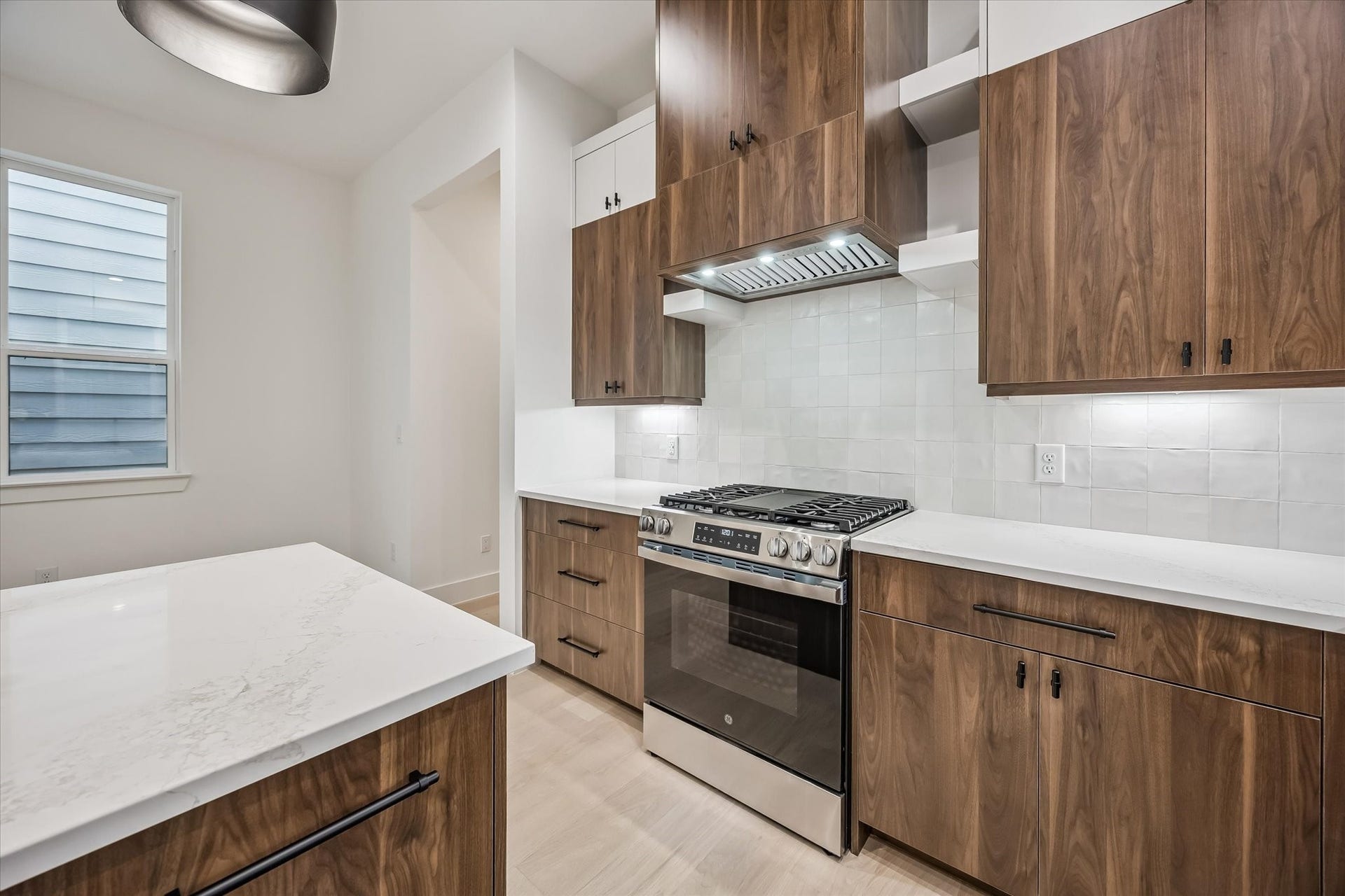 5339 Larkin Street, Houston, TX 77007 Modern kitchen with sleek wood cabinetry, a stainless steel gas range, and elegant white countertops.