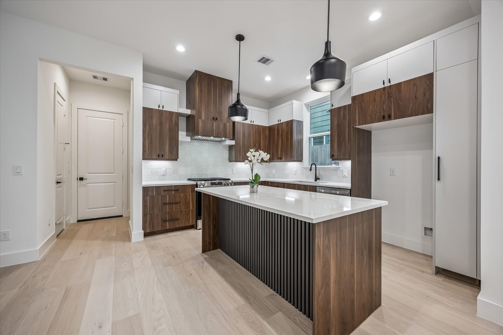 5339 Larkin Street, Houston, TX 77007 Sleek modern kitchen with elegant wood cabinetry and a spacious island, complemented by contemporary pendant lighting and light wood flooring.