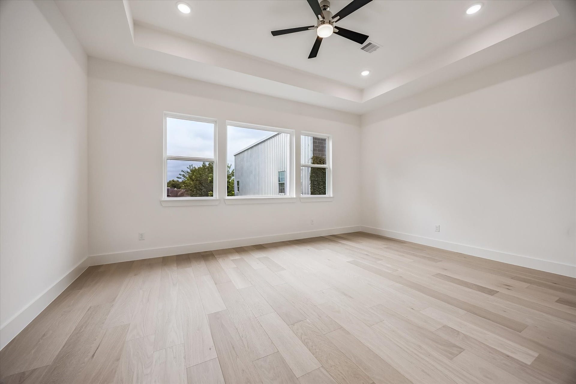 5339 Larkin Street, Houston, TX 77007 Spacious and bright room featuring light wood flooring, large windows, and a modern ceiling fan with recessed lighting.