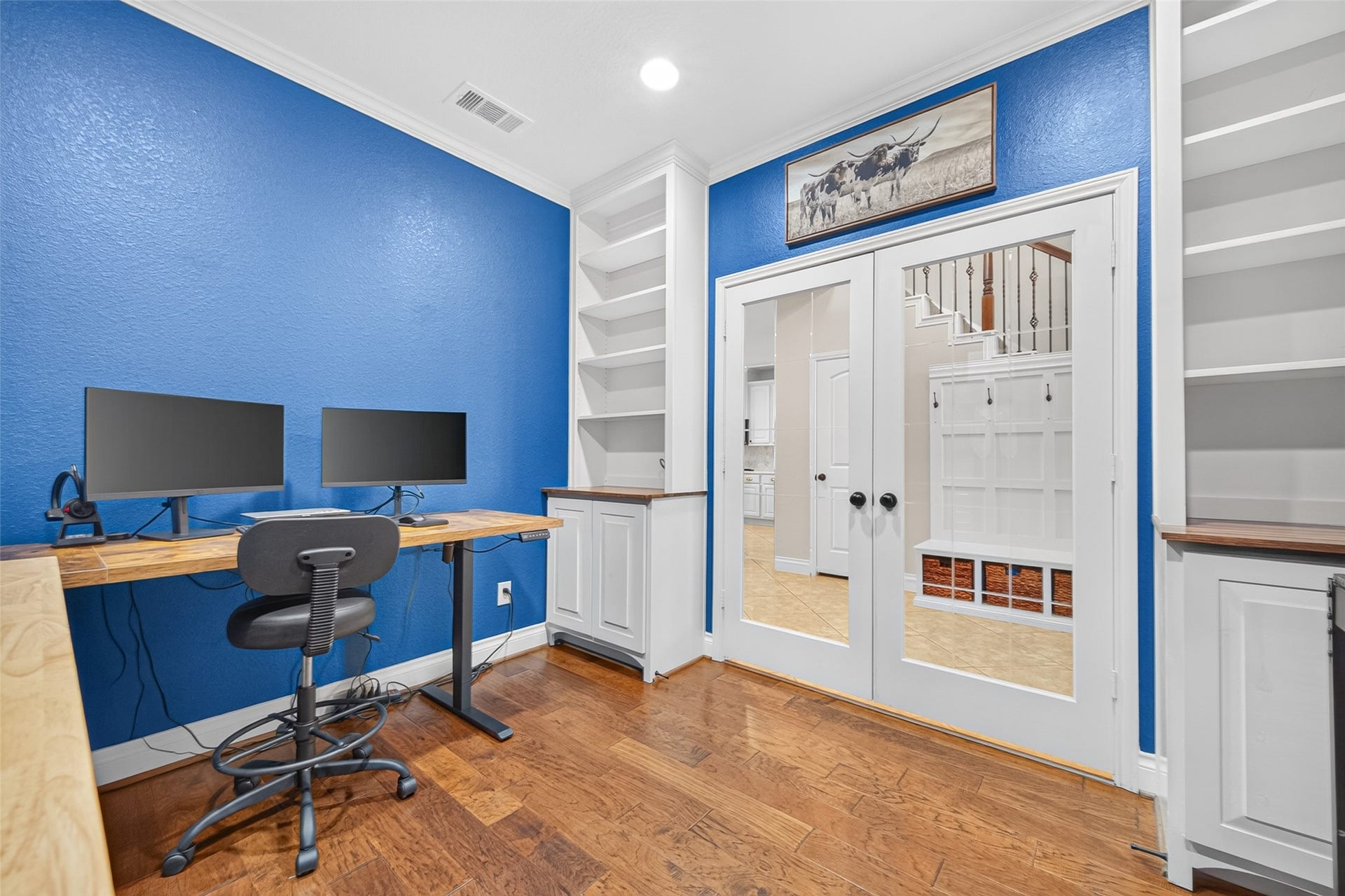 6710 Aqua Falls, Missouri City, TX 77459 Bright home office with vibrant blue walls, built-in shelving, and double glass doors, offering a perfect workspace with ample storage.