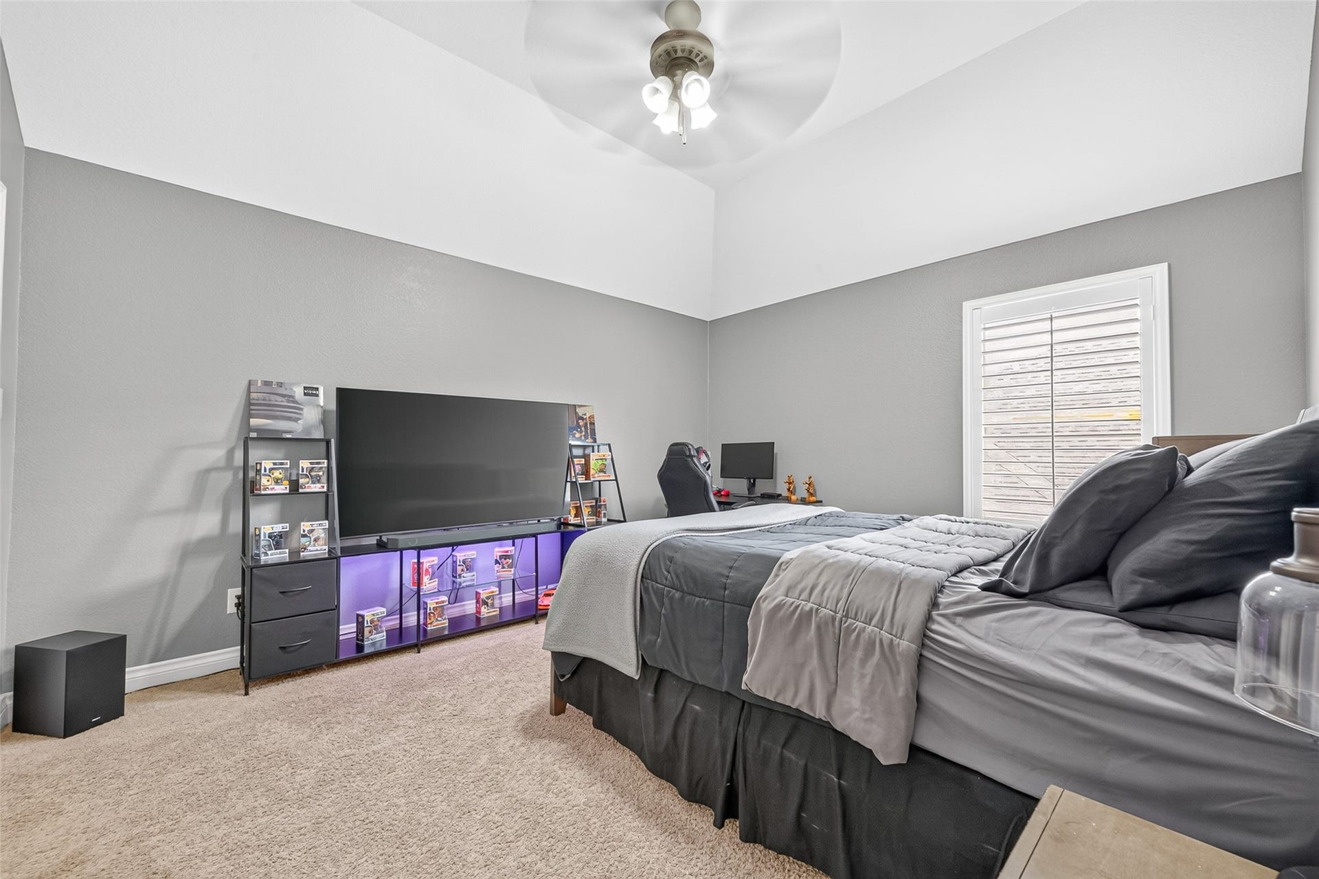 6710 Aqua Falls, Missouri City, TX 77459 Spacious bedroom with soft gray walls, cozy carpeting, and a ceiling fan. Features a comfortable workspace and twin bed, perfect for a home office or guest room.