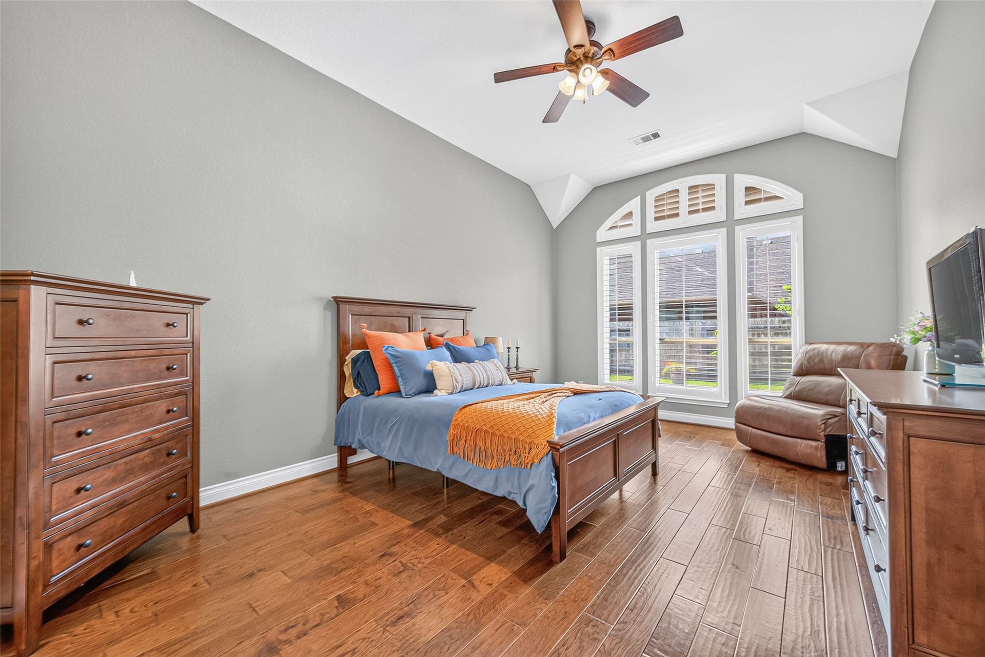 6710 Aqua Falls, Missouri City, TX 77459 Spacious bedroom featuring elegant wood flooring, a high ceiling with a fan, and large arched windows allowing plenty of natural light.