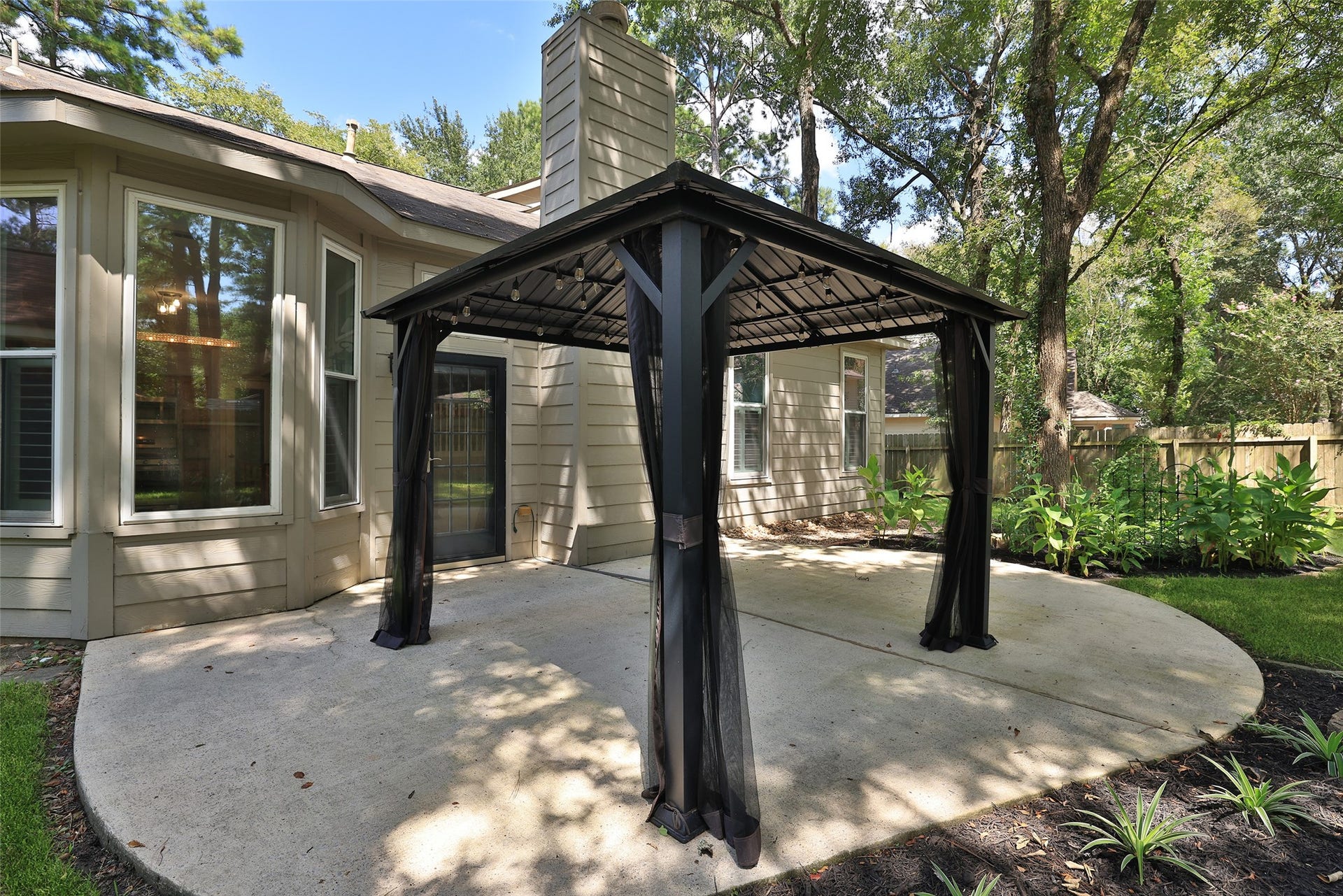 21 Long Hearth Place, The Woodlands, TX 77382 Backyard Permanent metal pergola with a solid roof creates a shaded outdoor living space.