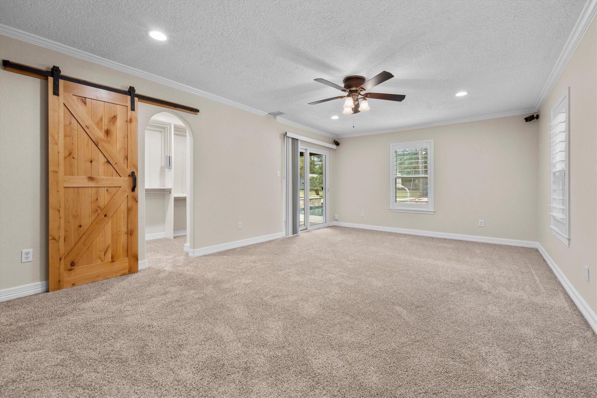 7119 Poole Road, Spring, TX 77379 The primary bedroom pairs charm with convenience, featuring a walk-in closet accented by a barn door and sliding glass doors opening to the pool area and wraparound porch.