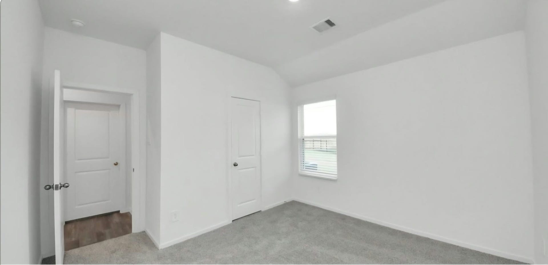 Bright secondary bedroom with soft carpeting and a neutral color palette.