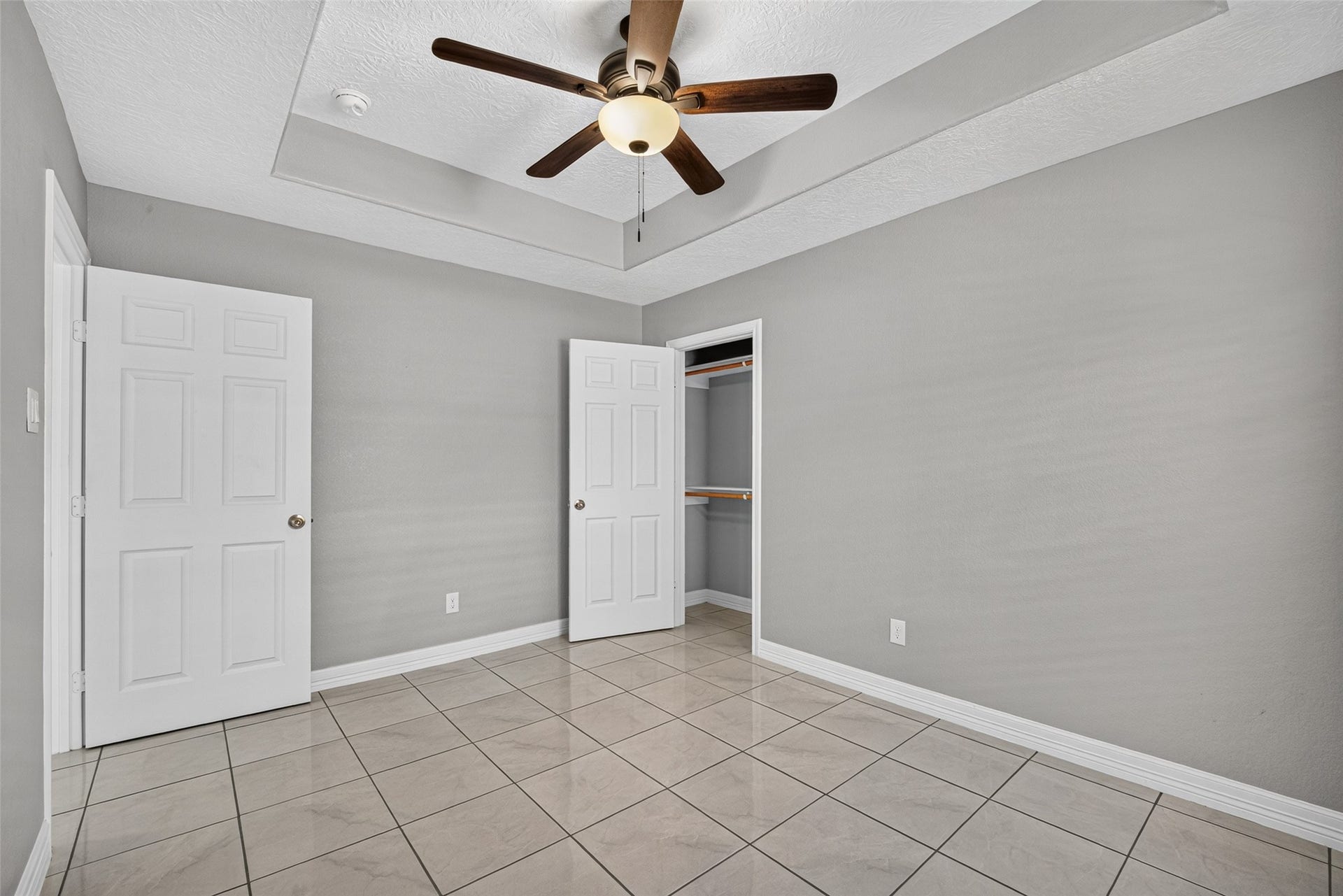 803 Avenue K, South Houston, TX 77587 Bright and spacious room featuring a modern ceiling fan, elegant tray ceiling, and sleek tile flooring.