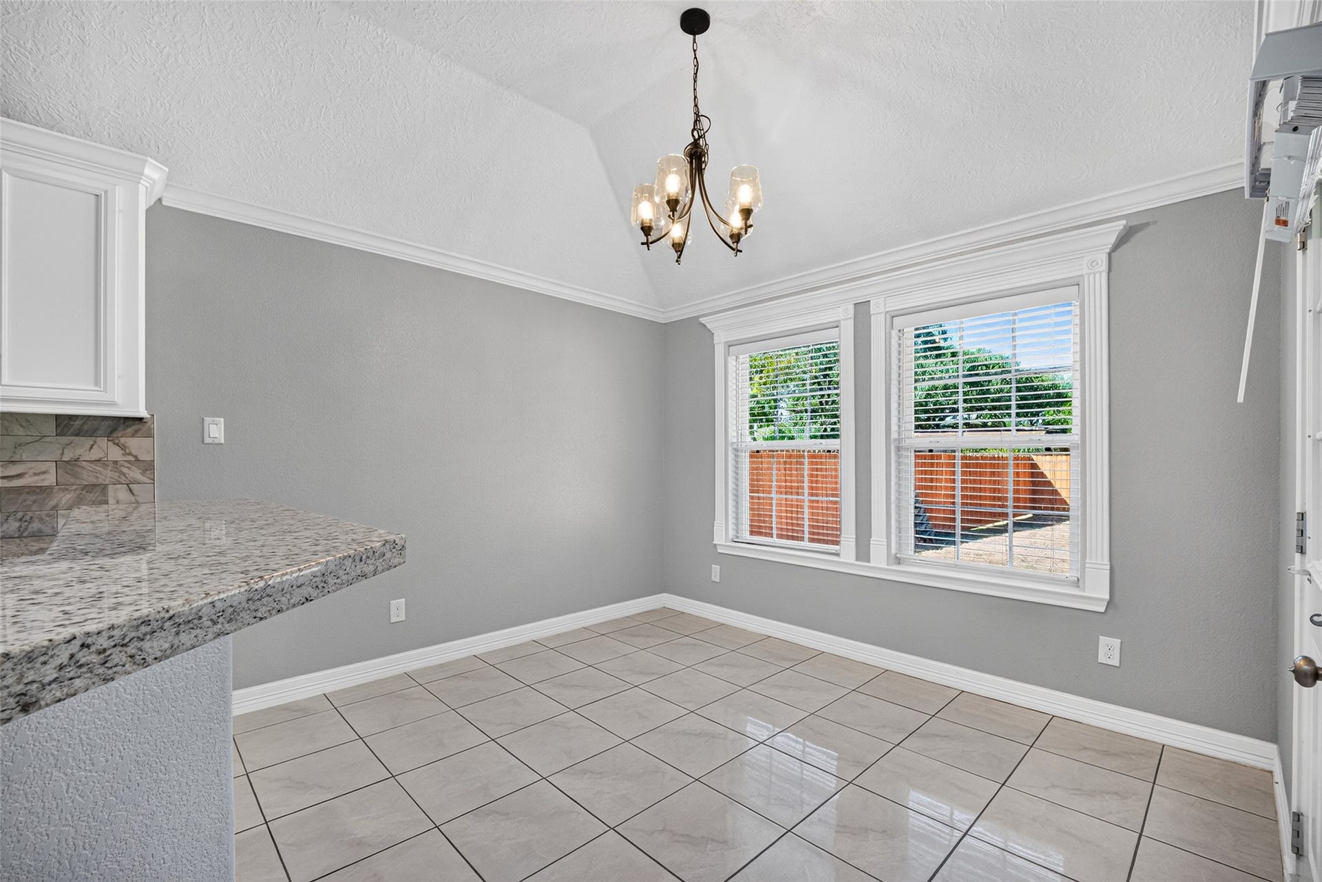 803 Avenue K, South Houston, TX 77587 Bright dining area with vaulted ceiling, elegant chandelier, and large windows offering plenty of natural light. Stylish tile flooring and a sleek granite breakfast bar add a modern touch.