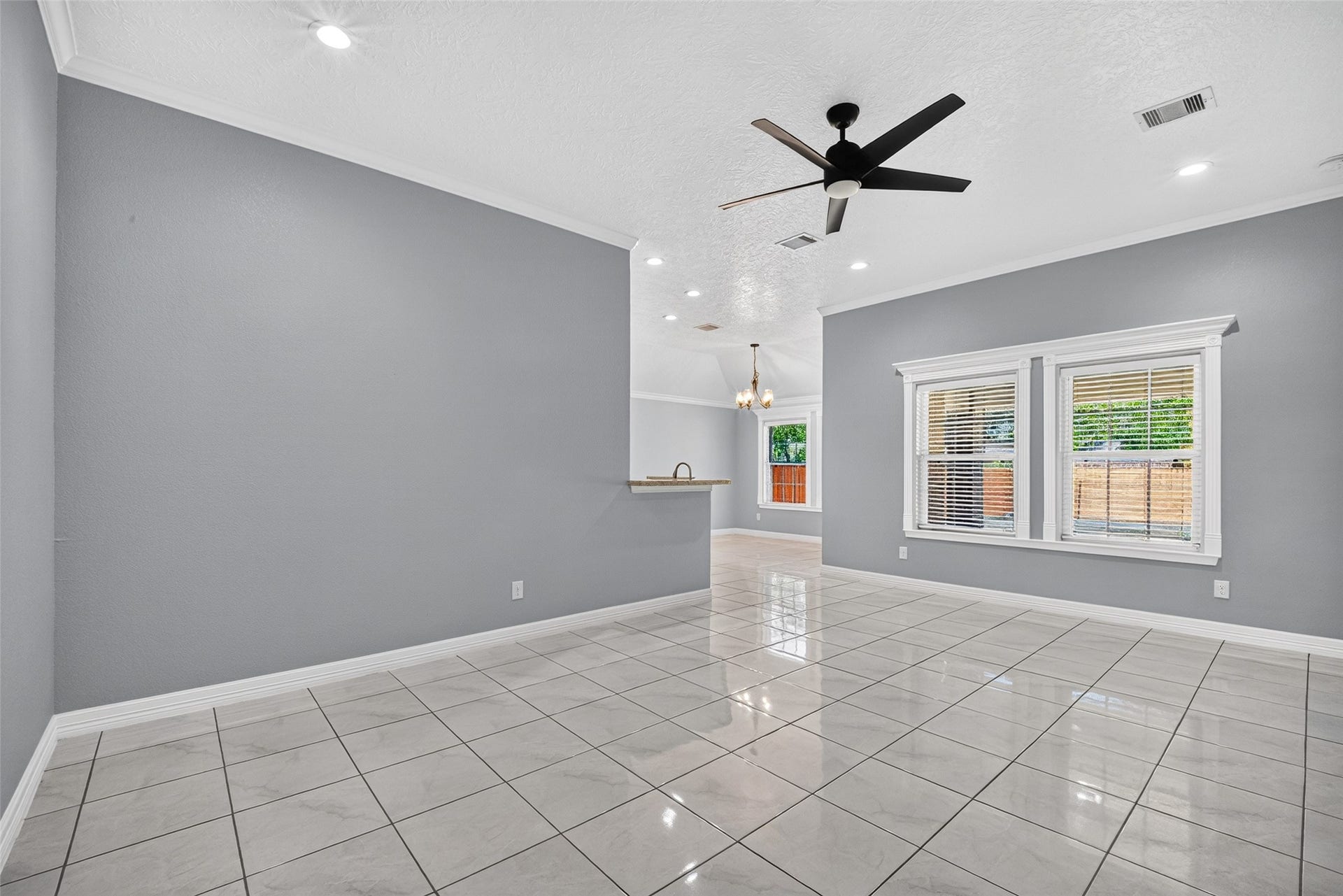 803 Avenue K, South Houston, TX 77587 Bright and spacious living area with sleek tile flooring, modern ceiling fan, and large windows for ample natural light, seamlessly flowing into an open kitchen with elegant finishes.