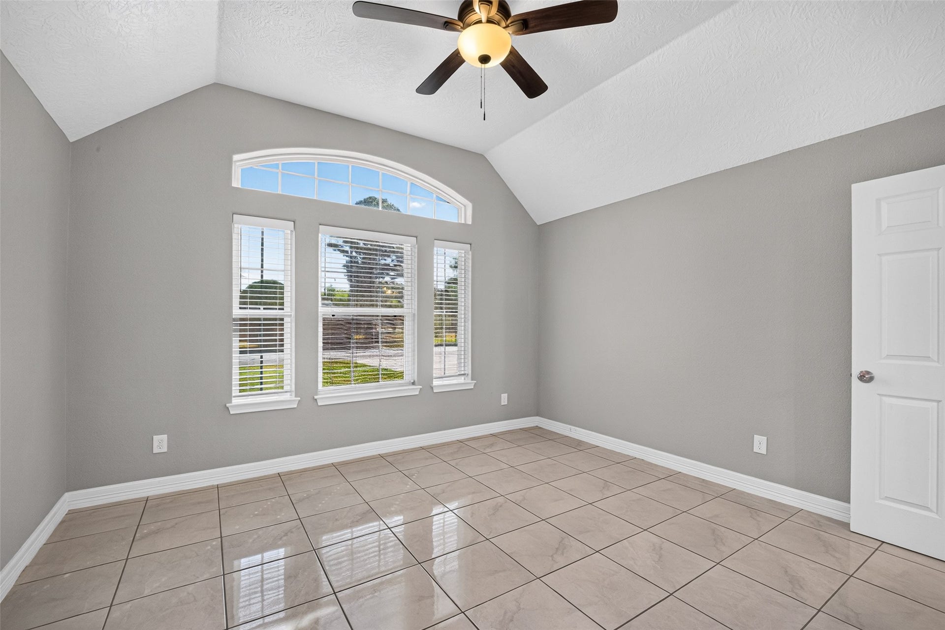 803 Avenue K, South Houston, TX 77587 Bright and inviting secondary bedroom featuring a high ceiling, elegant tile flooring, and a large arched window that fills the space with natural light.