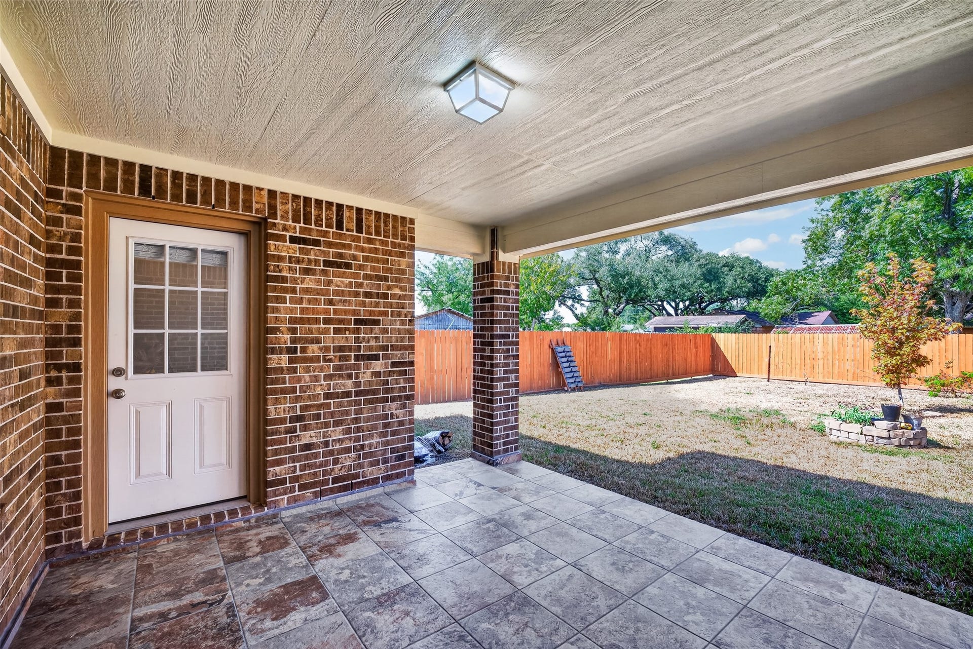 803 Avenue K, South Houston, TX 77587 Charming covered patio with elegant brick walls and stylish tile flooring, perfect for outdoor relaxation and entertaining.