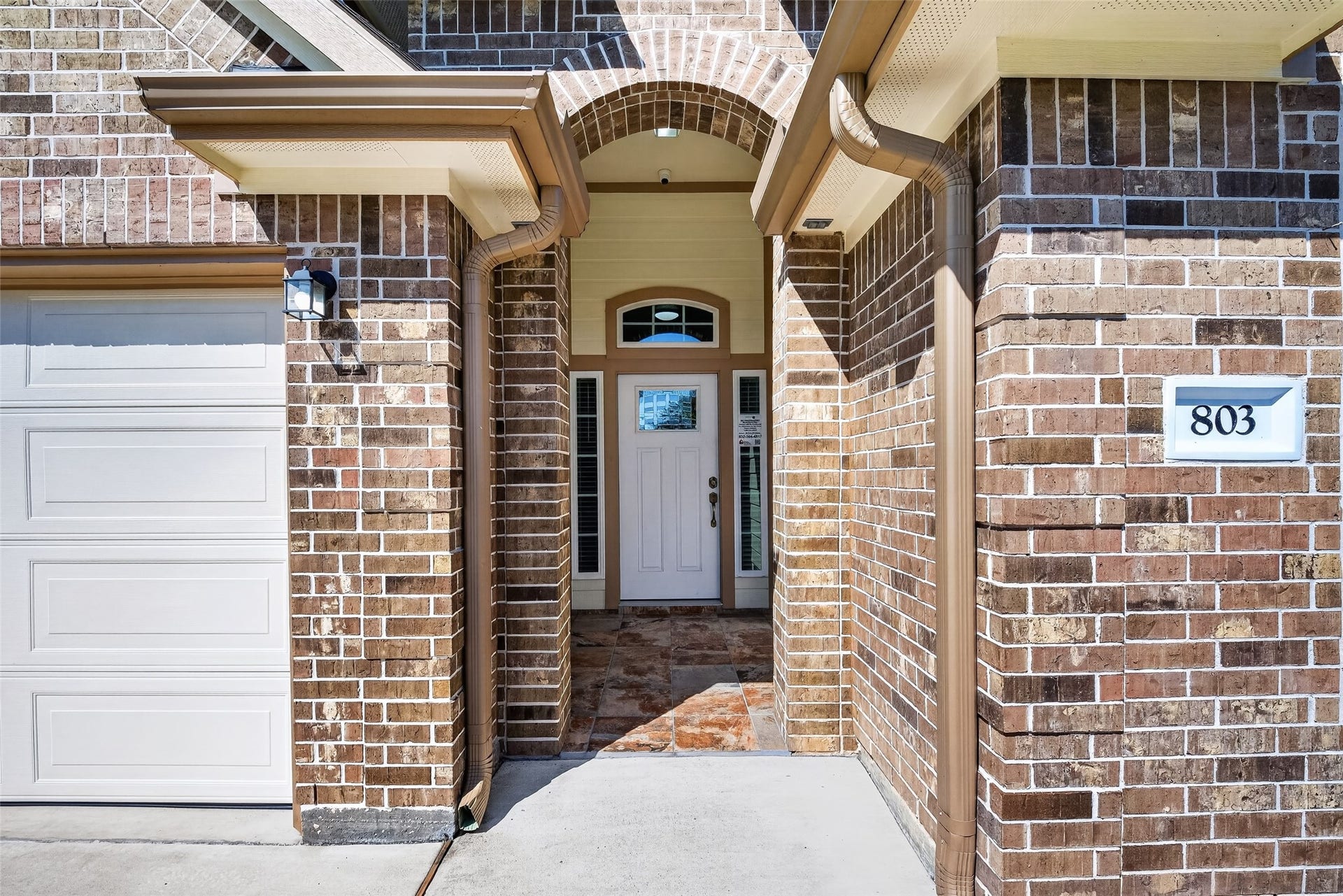 803 Avenue K, South Houston, TX 77587 Charming brick exterior with a welcoming arched entryway, complemented by a classic white door and adjacent garage.
