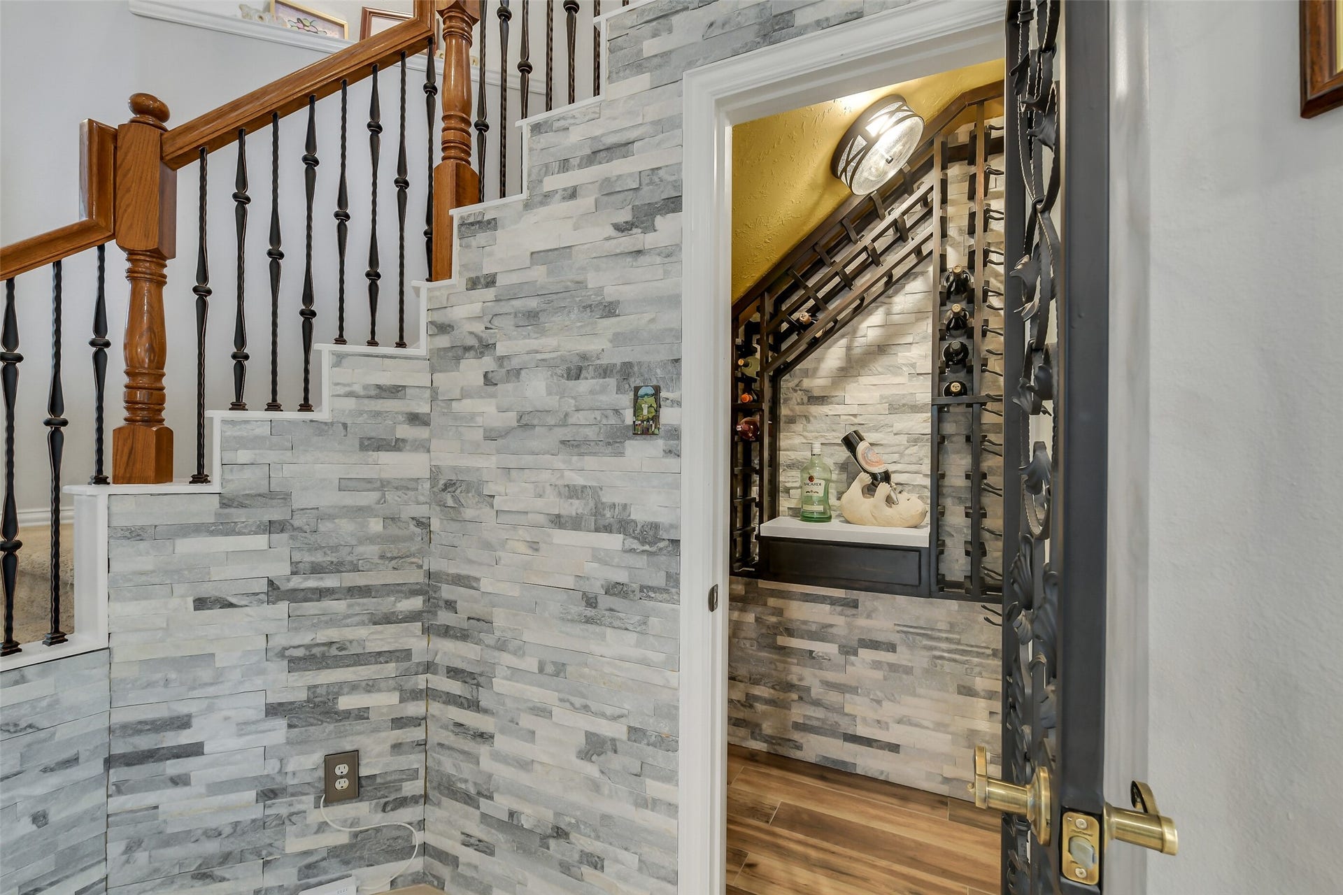 7 Larkspur Trail, The Woodlands, TX 77382 Charming under-stair wine cellar features elegant stone walls and stylish iron door, perfect for wine enthusiasts.