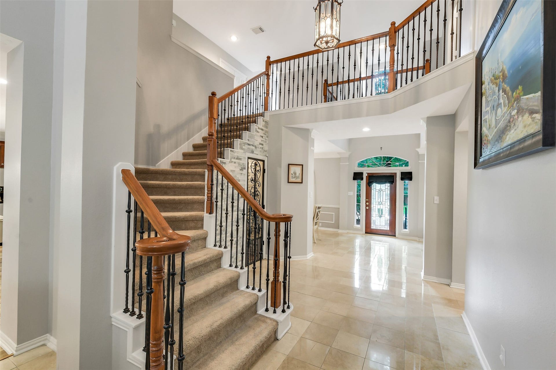 7 Larkspur Trail, The Woodlands, TX 77382 Elegant foyer featuring a grand staircase with wrought iron spindles, polished tile floors, and a welcoming grand-door entrance.