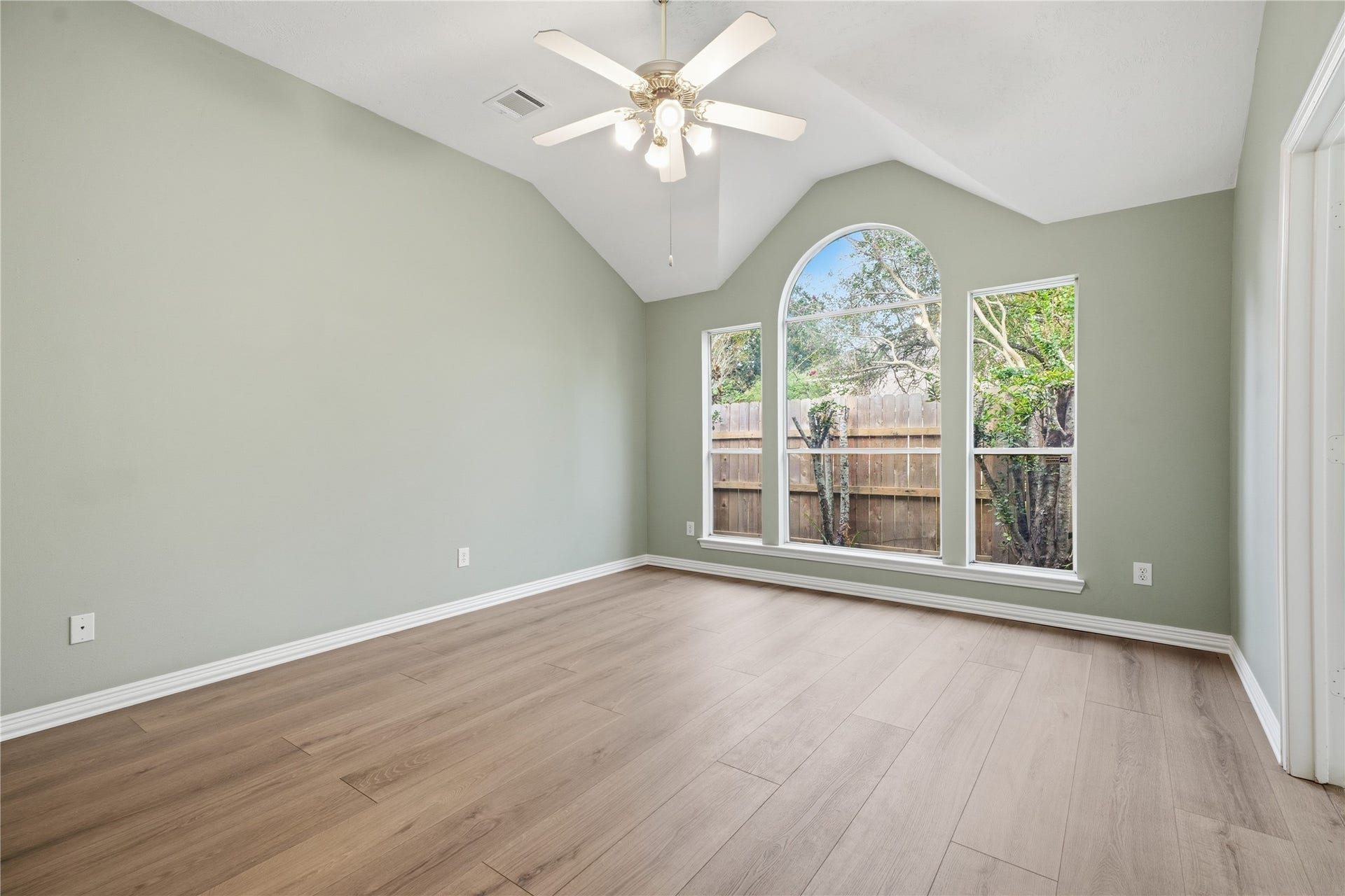 1411 Pebble Banks Lane, Seabrook, TX 77586 Spacious primary suite offering vaulted ceilings, a central ceiling fan, and soft sage walls.