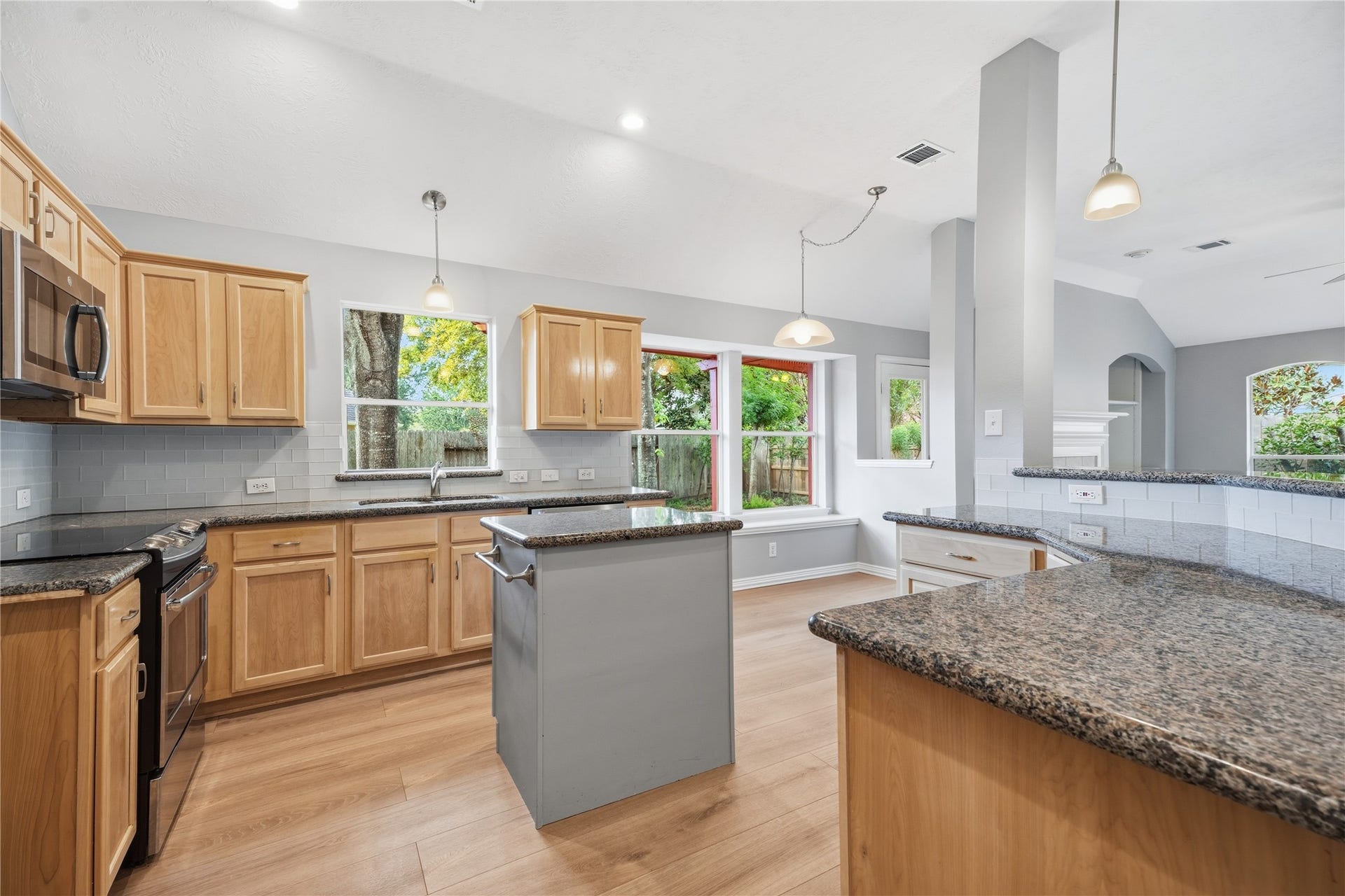 1411 Pebble Banks Lane, Seabrook, TX 77586 Bright open concept kitchen featuring granite countertops, warm wood cabinetry, subway tile backsplash and a central prep island.
