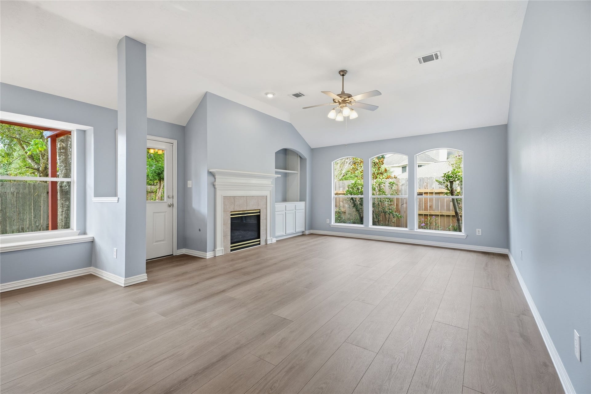 1411 Pebble Banks Lane, Seabrook, TX 77586 Spacious family room featuring high vaulted ceilings, a cooling ceiling fan, and the continuous neutral vinyl plank flooring.