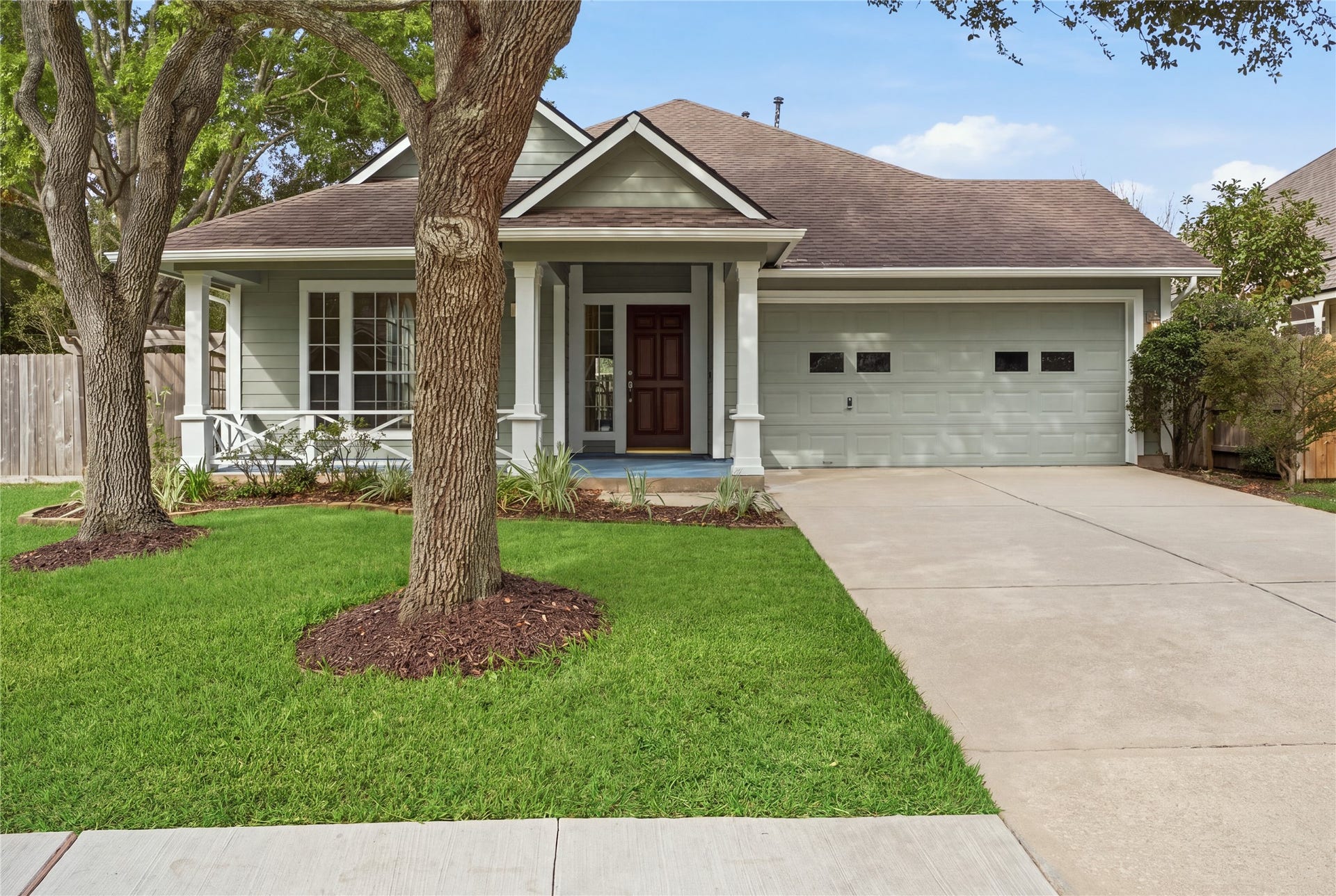 1411 Pebble Banks Lane, Seabrook, TX 77586 Charmingly shaded single-story home featuring a sage green exterior with crisp white trim.