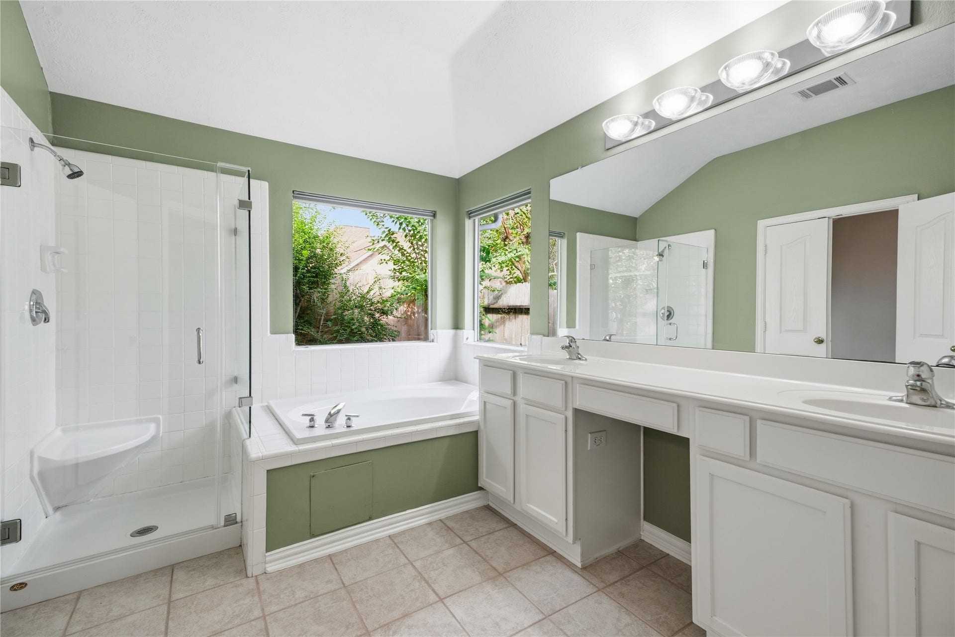 1411 Pebble Banks Lane, Seabrook, TX 77586 Spa-like primary bath boasting double vanity sinks, makeup vanity area, expansive mirror and modern vanity light fixtures.