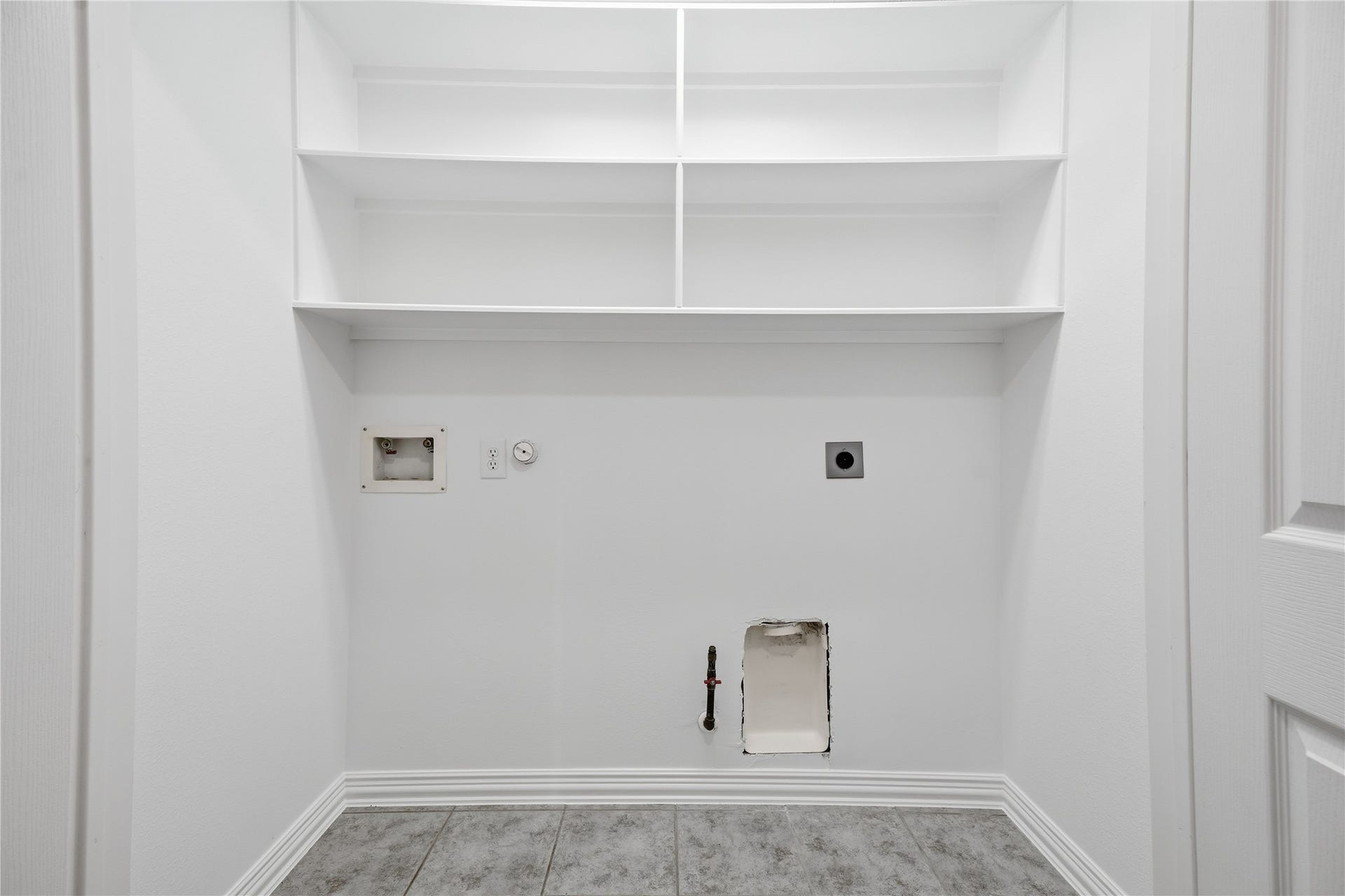 1411 Pebble Banks Lane, Seabrook, TX 77586 Dedicated indoor utility, durable tile flooring and built-in overhead open shelving for convenient laundry organization and storage needs.
