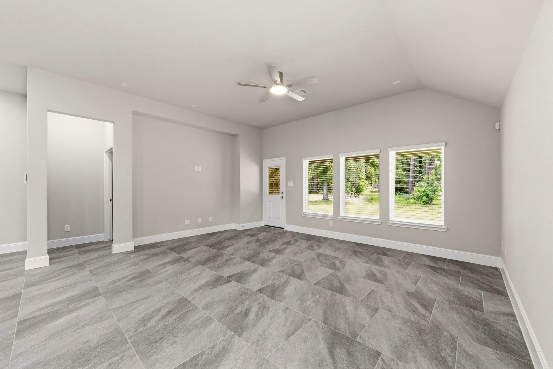 23620 Youpon Lane, Spring, TX 77389 Light filled living room with vaulted ceilings, elegant tile flooring, and tranquil backyard views.