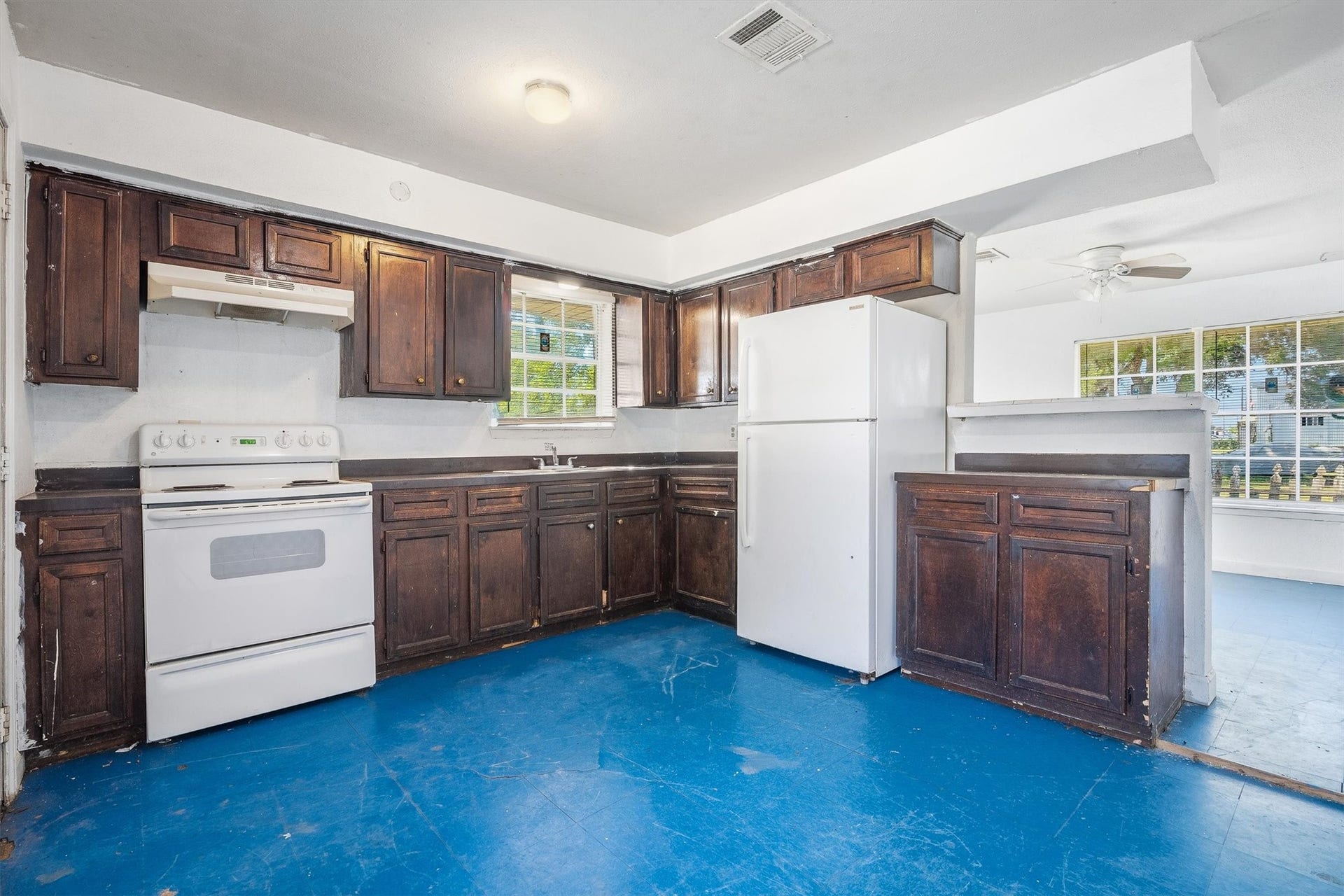 3218 5th Street, Stafford, TX 77477 The kitchen showcases rich, dark-stained cabinetry paired with distinctive blue tile flooring, creating a bold contrast and adding character to this functional space.