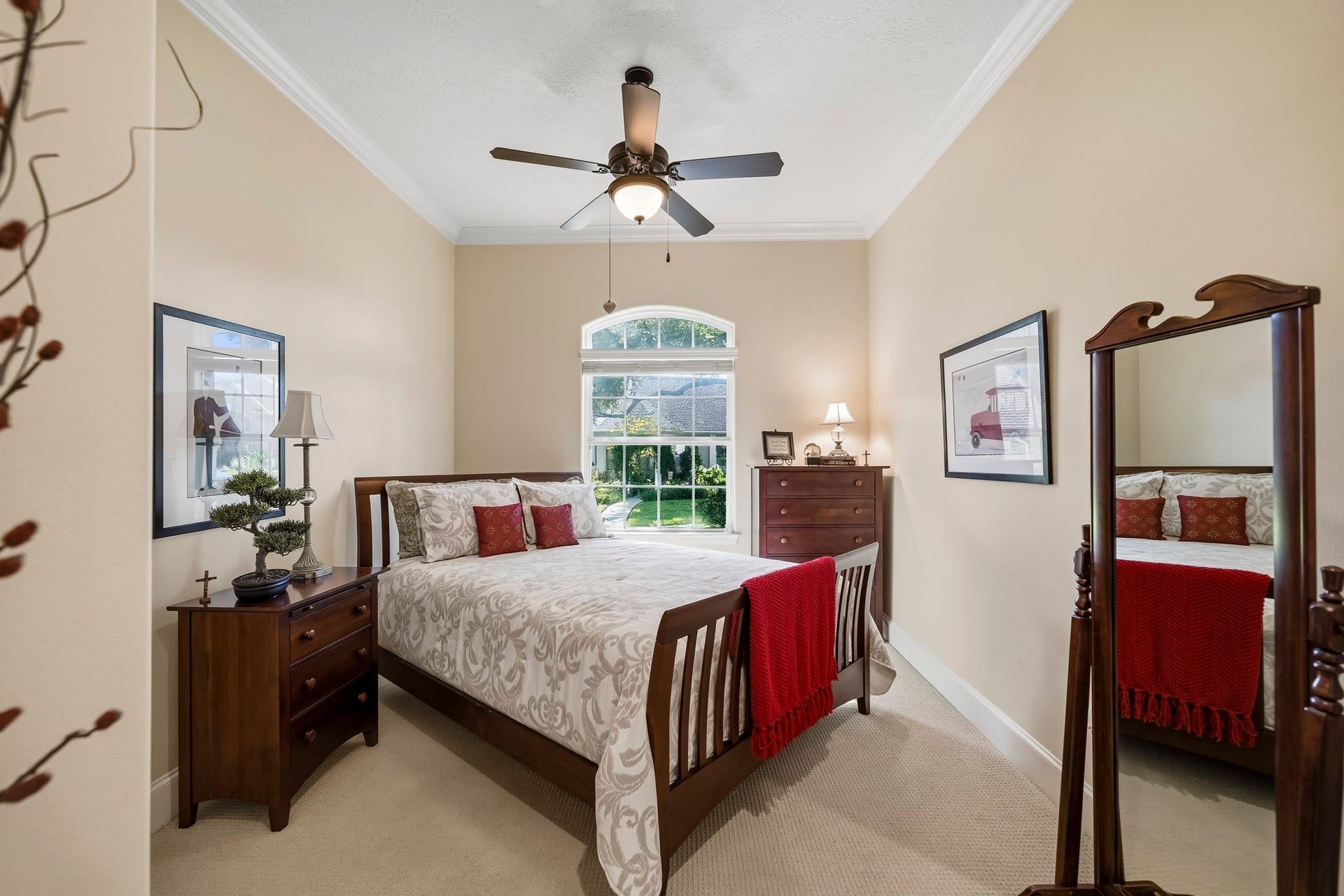 4631 Lake Village Drive, Fulshear, TX 77441 This Secondary Bedroom combines comfort and character, featuring durable carpeting, elegant crown molding, a 5-blade ceiling fan, and a spacious walk-in closet. An expansive window crowned by a graceful arched transom fills the room with natural light while framing serene views of the lush Front Yard, creating a bright and inviting retreat.