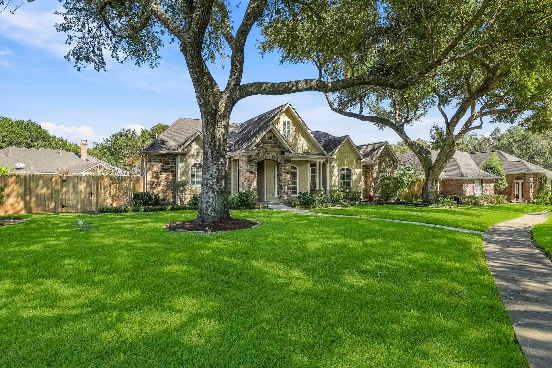 4631 Lake Village Drive, Fulshear, TX 77441 A magnificent pair of mature live oak trees stretches gracefully overhead, creating a lush canopy that blankets the front yard in refreshing, dappled shade.