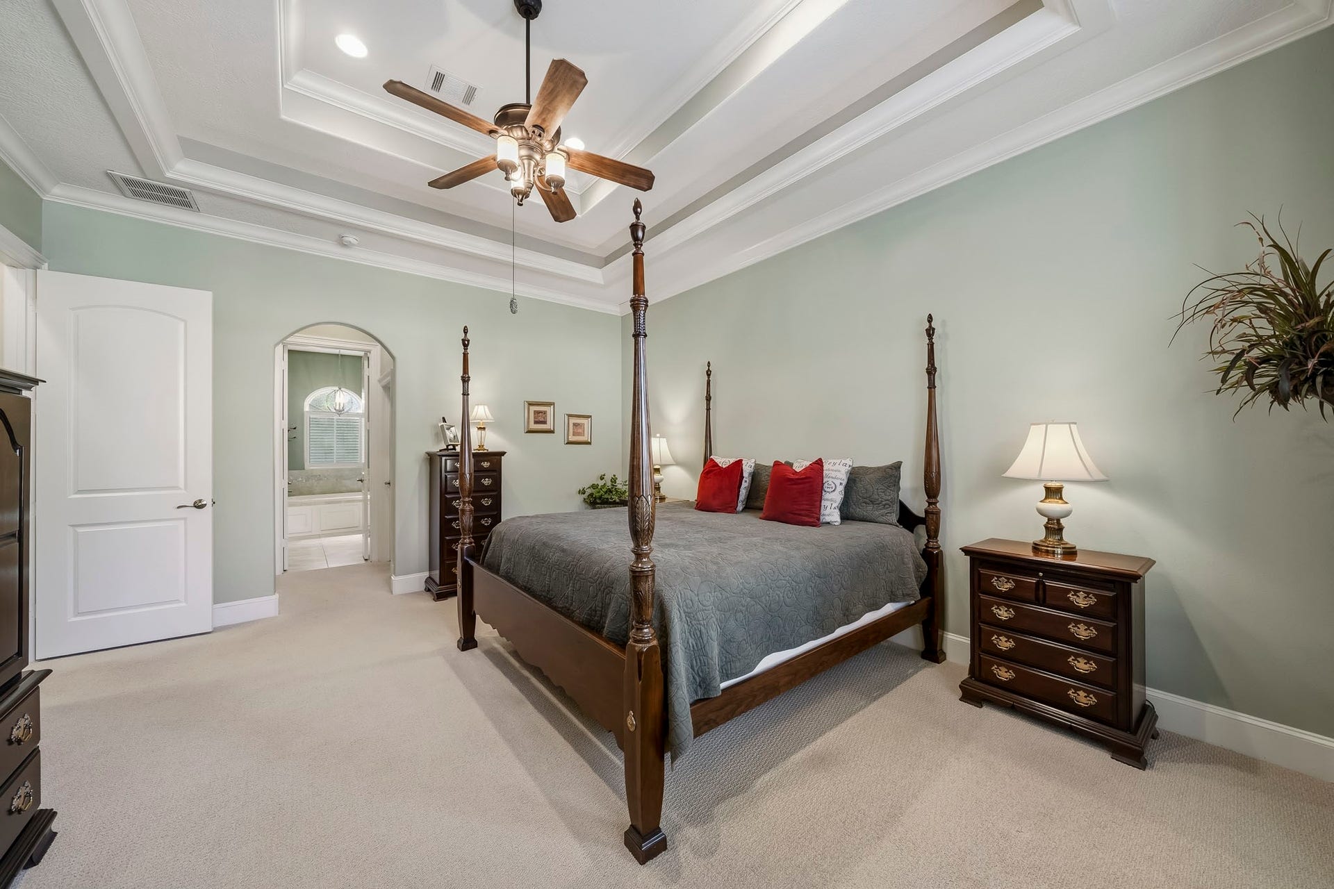 4631 Lake Village Drive, Fulshear, TX 77441 This spacious Primary Bedroom exudes comfort and sophistication, featuring plush carpeting underfoot, a soothing green palette, elegant crown molding, and a striking double tray ceiling that draws the eye upward and enhances the room's sense of scale.