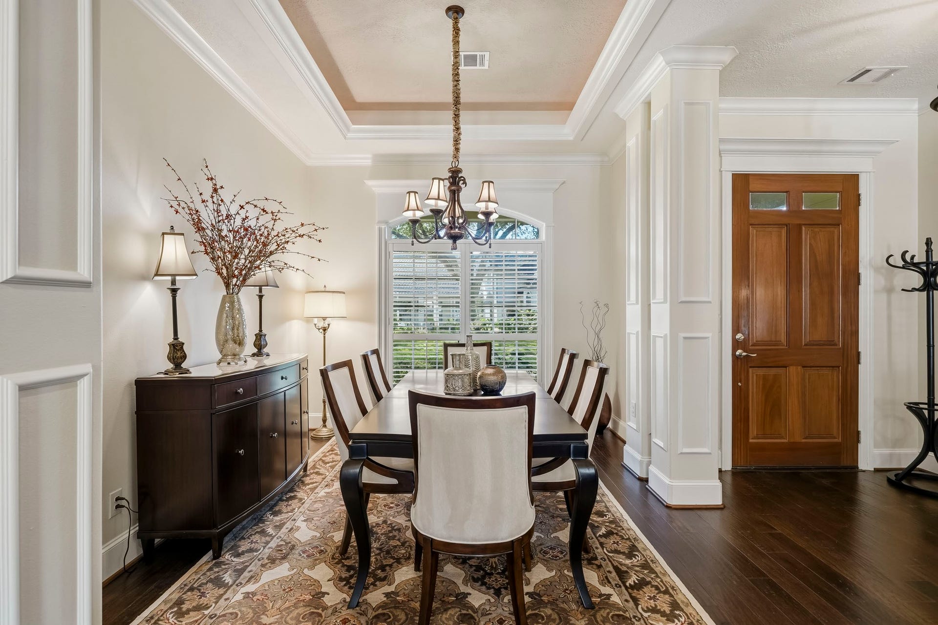 4631 Lake Village Drive, Fulshear, TX 77441 The Dining Room, ideally situated just off the Foyer, is awash in natural light streaming through a stunning arched window. Exquisite double crown molding, a dramatic tray ceiling, and elegantly cased pillars add architectural distinction, creating a refined space that is equally suited for intimate dinners and memorable gatherings.