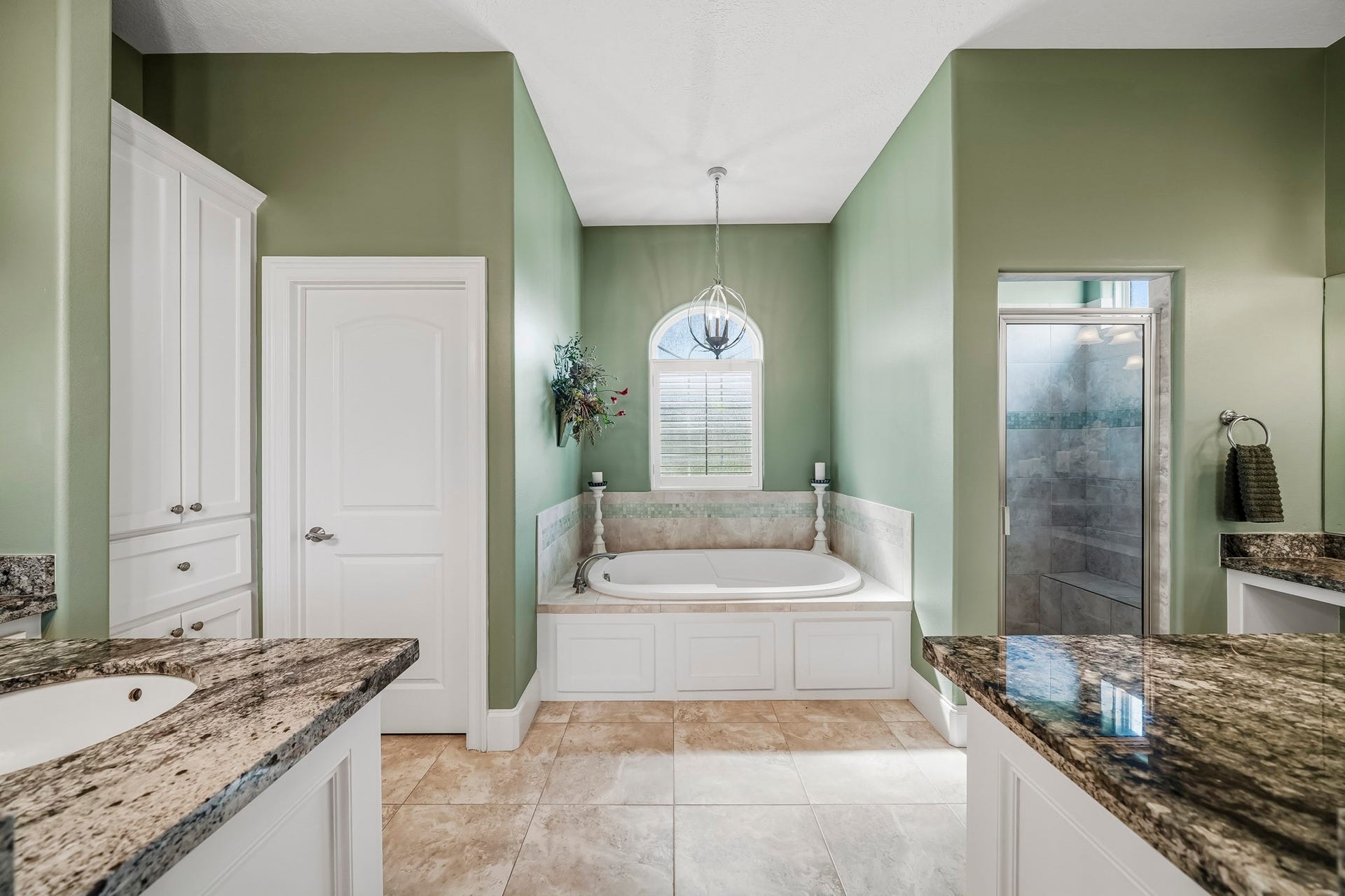4631 Lake Village Drive, Fulshear, TX 77441 Unwind in the tranquil comfort of this spa-inspired Primary Bathroom, where rich, moody green tones create a warm and relaxing ambiance. Crisp white cabinetry provides a striking contrast, lending the space a bright, polished elegance that feels both timeless and refined.