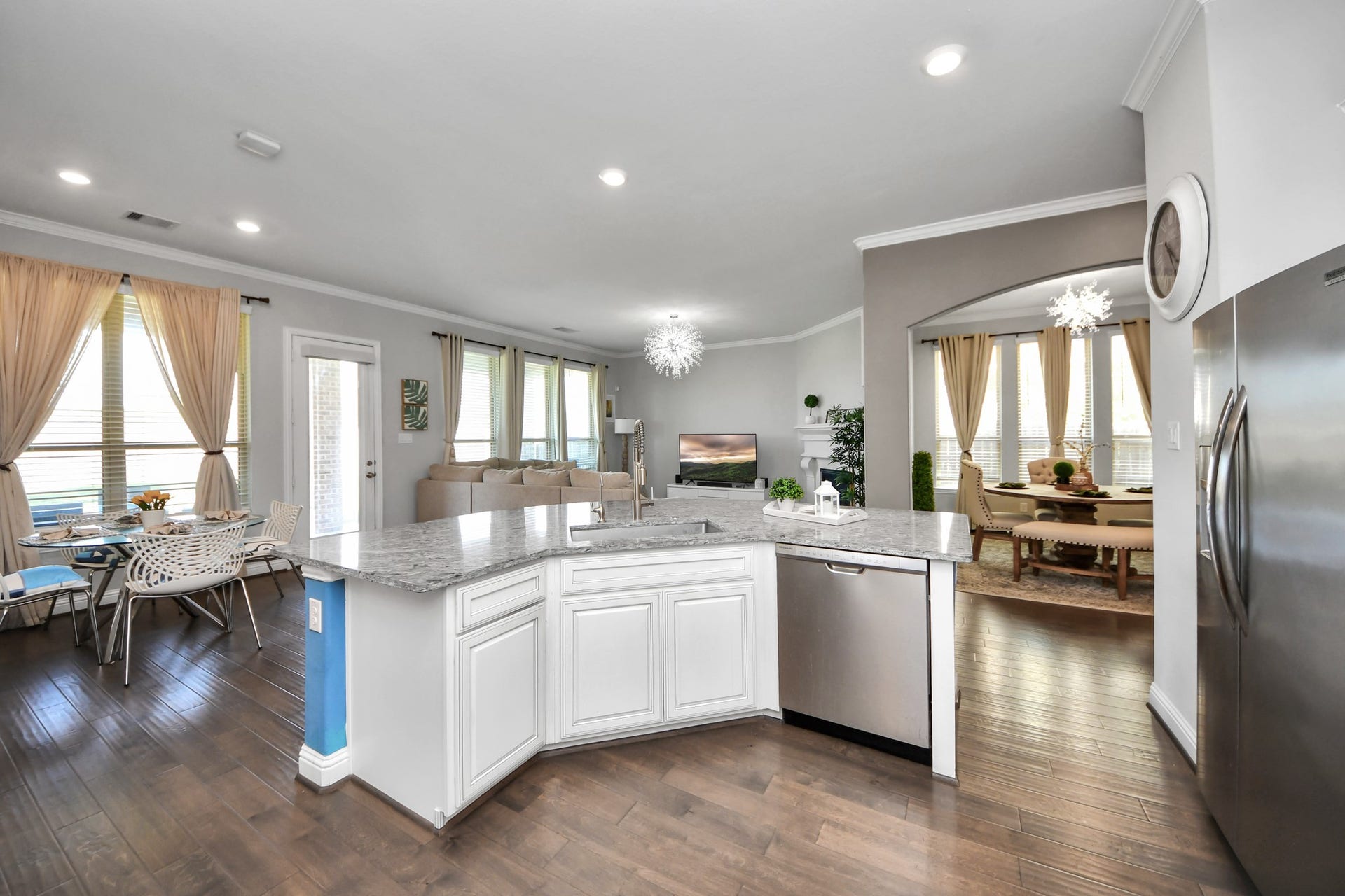 This spacious open-concept kitchen and living area features a large granite island, stainless steel appliances, and ample natural light. The dining and living spaces are elegantly integrated, with hardwood floors and modern fixtures creating a warm, inviting atmosphere.