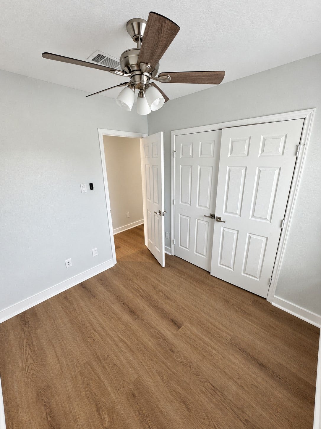 Additional bedroom view with neutral finishes and wood-look flooring.