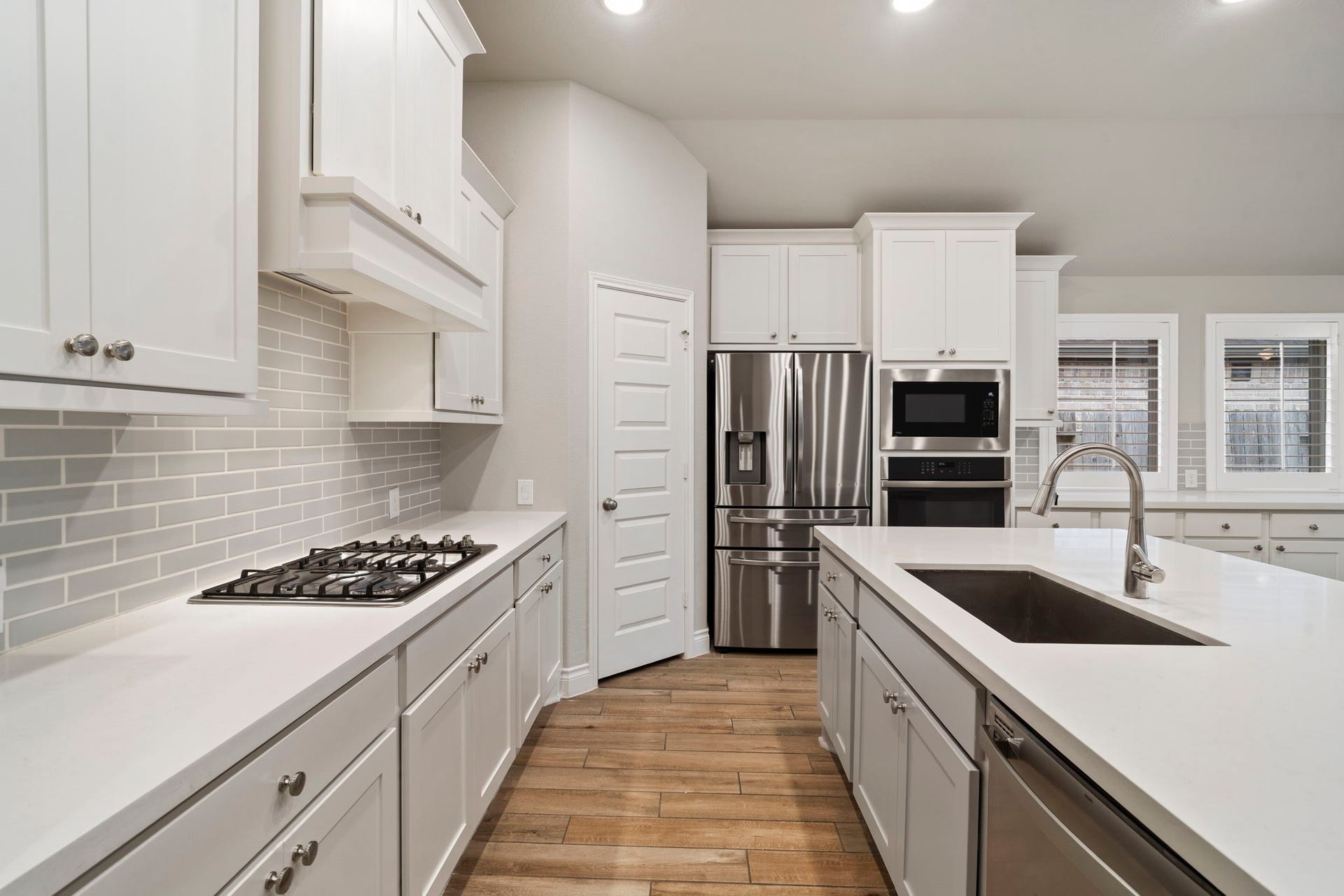 2315 Calm Channel Court, Missouri City, TX 77459 Immaculate and timeless, the kitchen pairs pristine white cabinetry and quartz countertops with soft gray subway tile for a fresh, sophisticated look that never goes out of style.