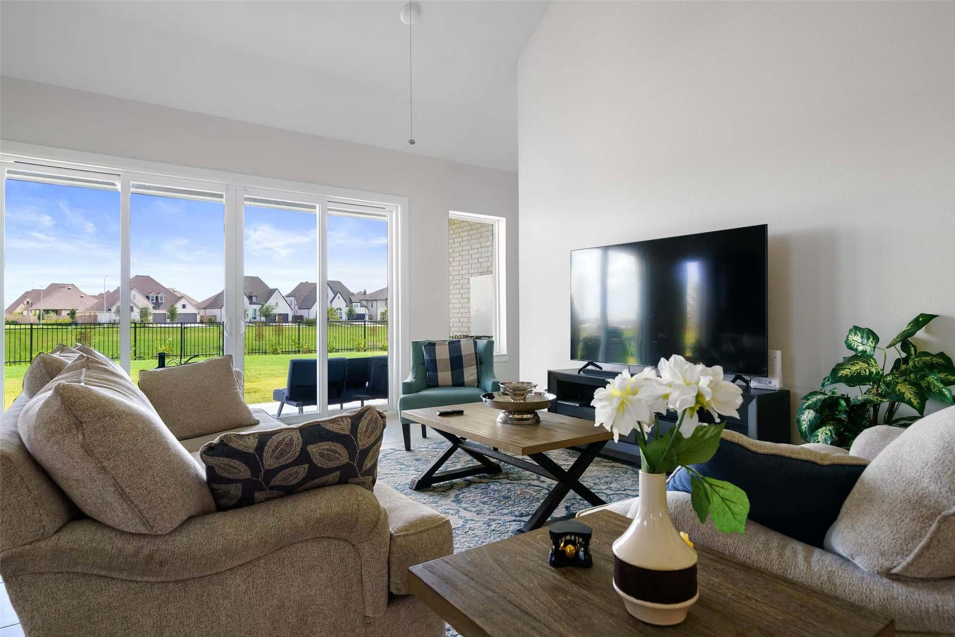 Bright and spacious living room featuring soaring ceilings and expansive sliding glass doors that fill the space with natural light and offer beautiful lake views.